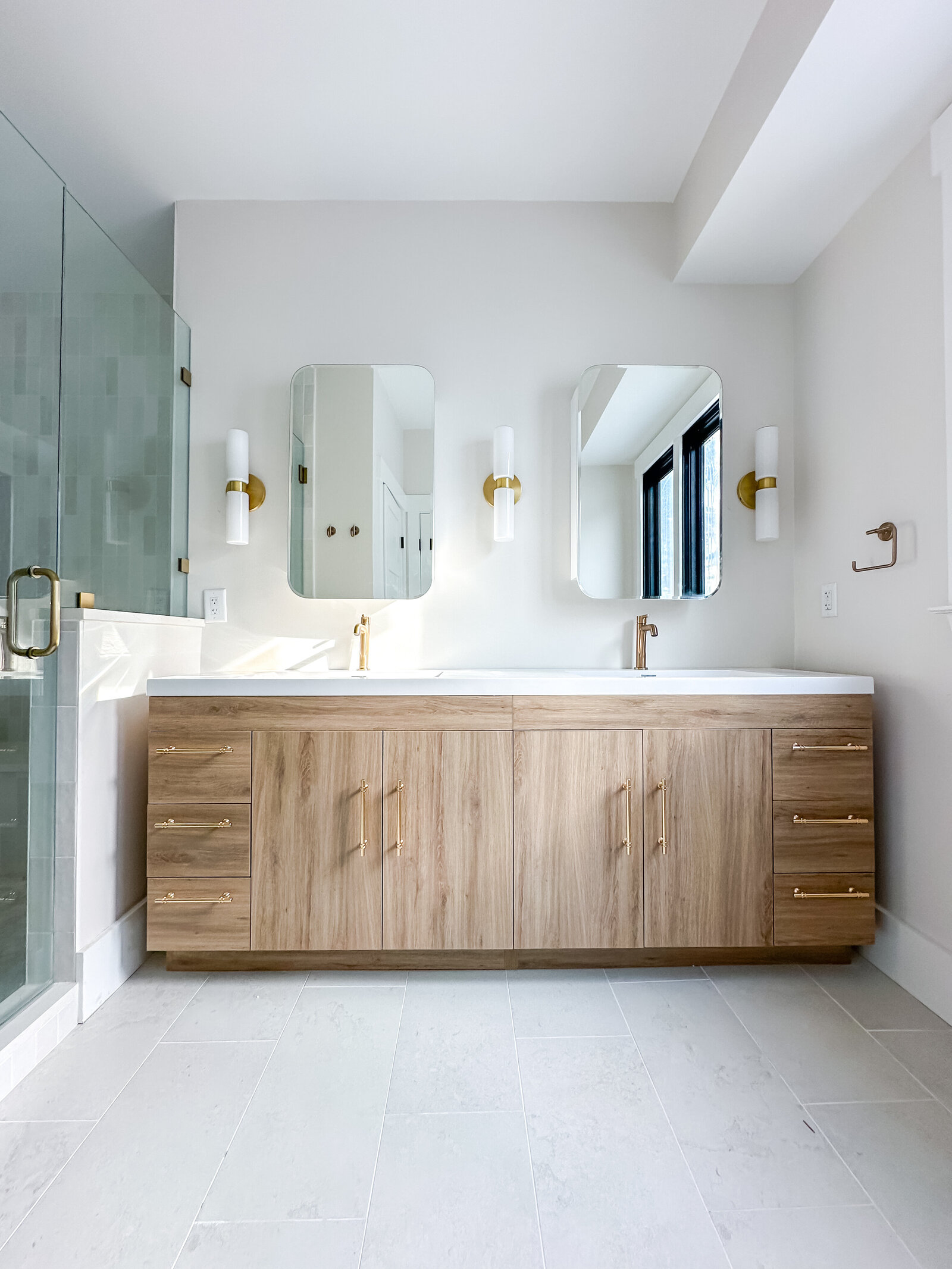 Neutral coastal master bathroom with double vanity and sconce lights.
