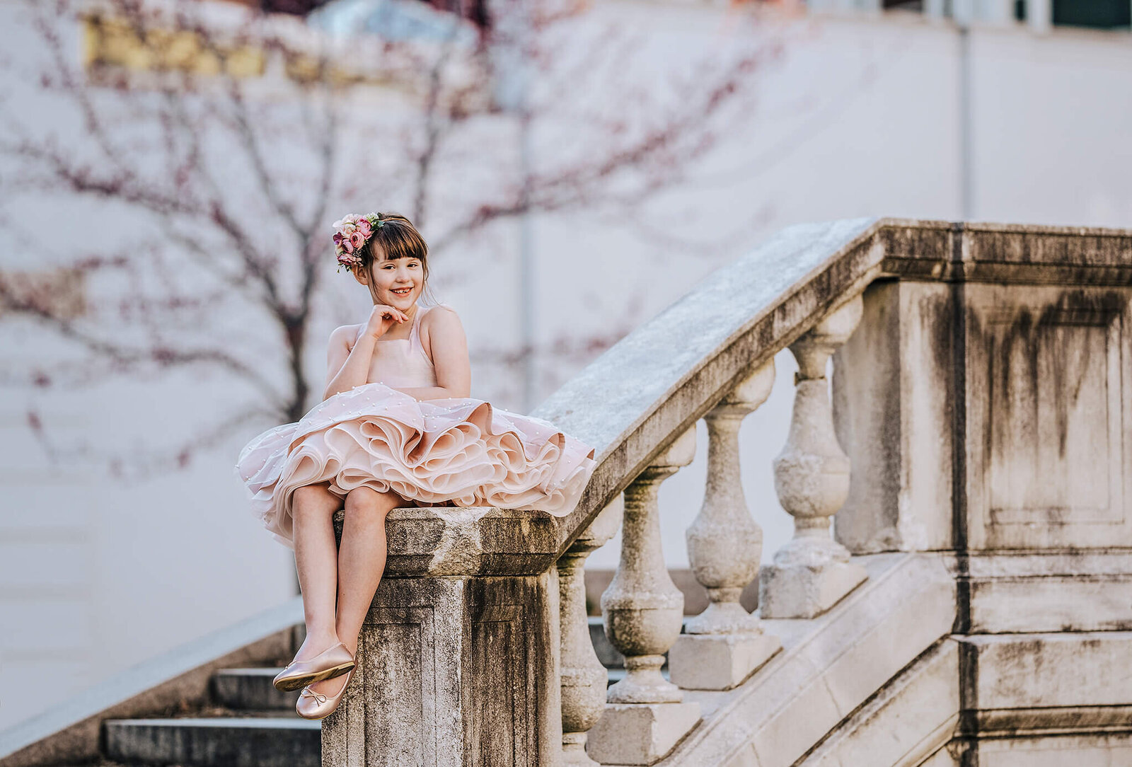 Girl in a pink dress sitting on white column steps in Mount Vernon Baltimore Maryland