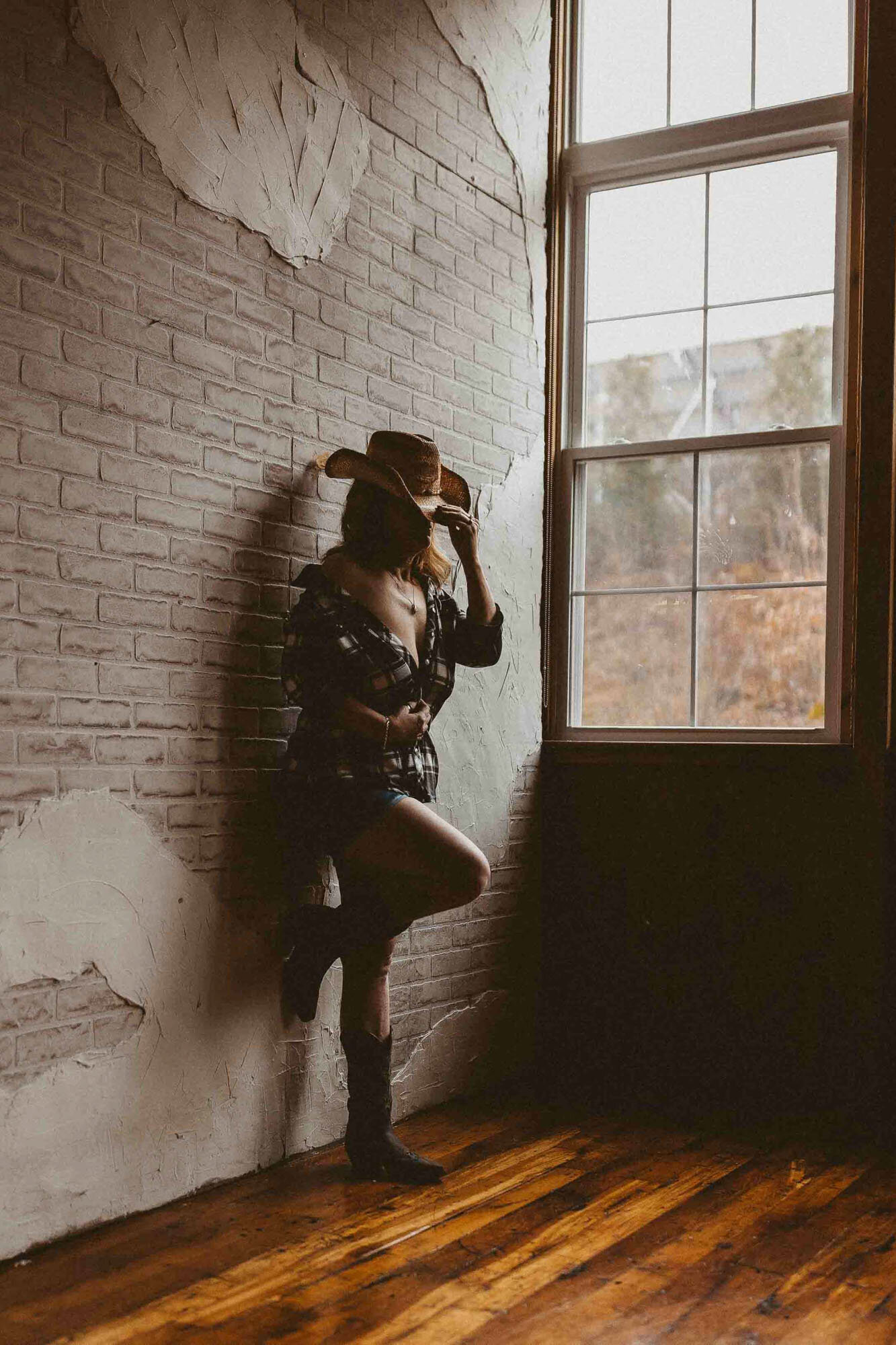 woman with a cowboy hat leaning on the wall