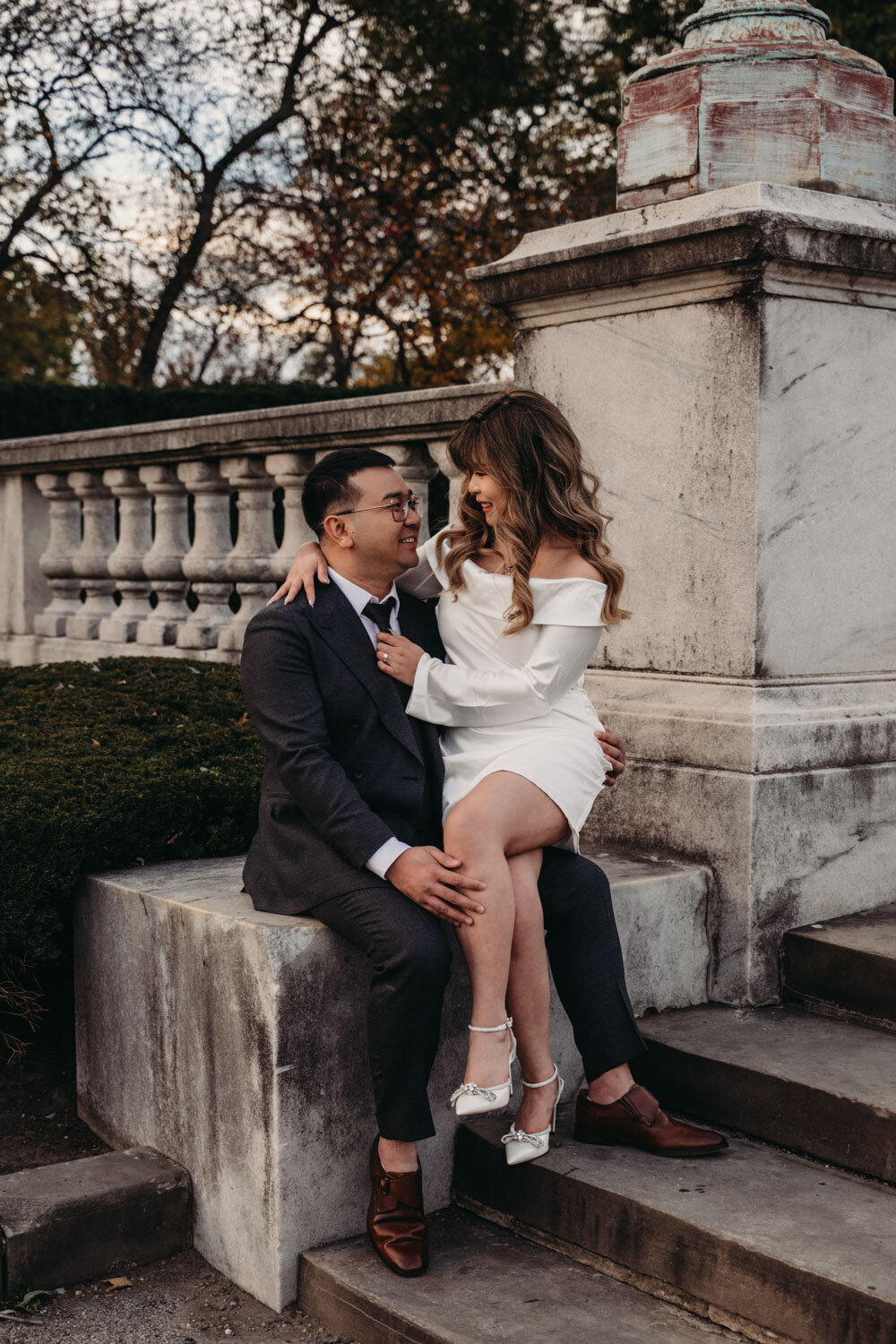 Couple sit on marble steps in formal attire for session