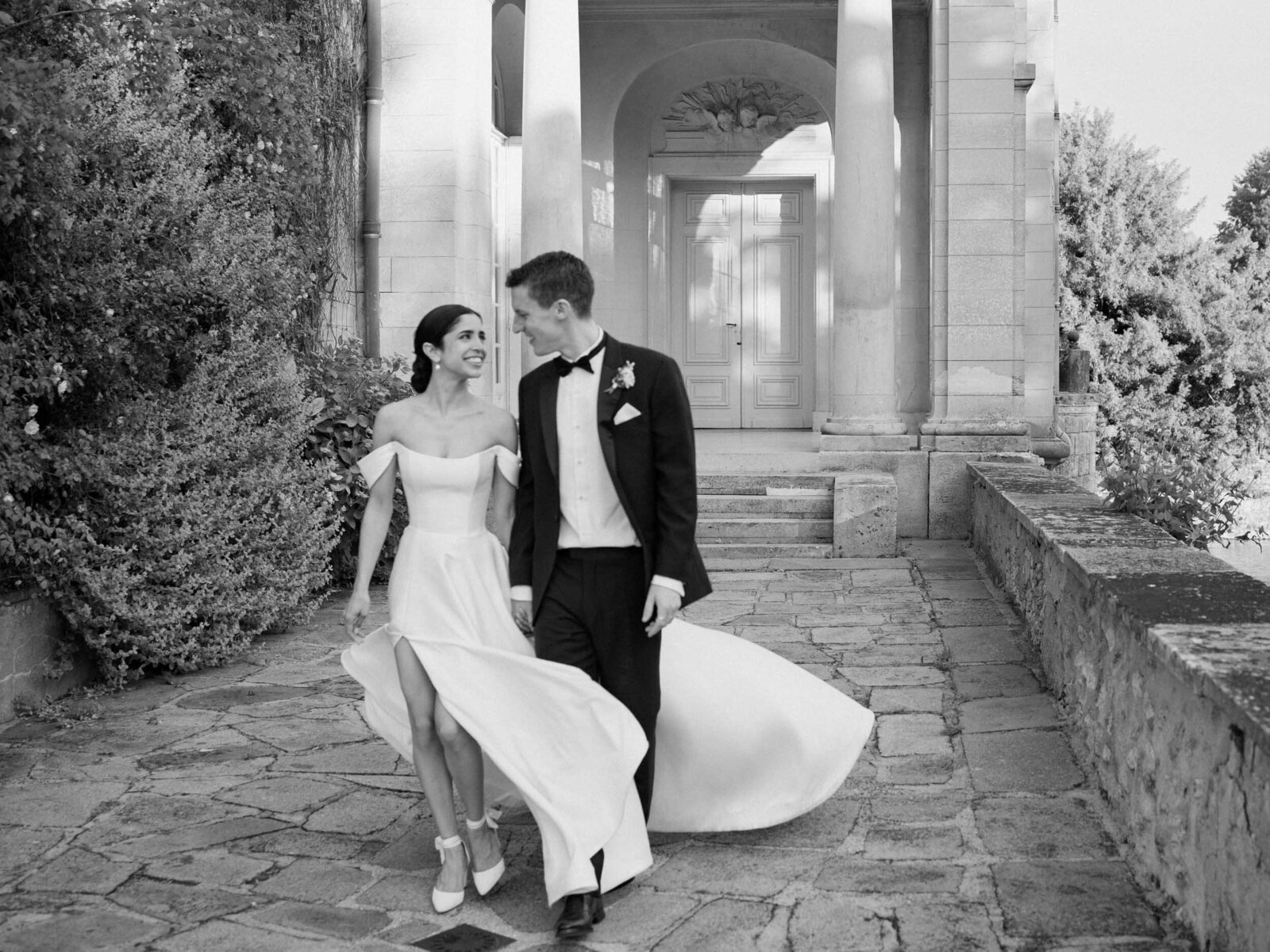 A newly married couple walking together in front of a French château during their Paris destination wedding.