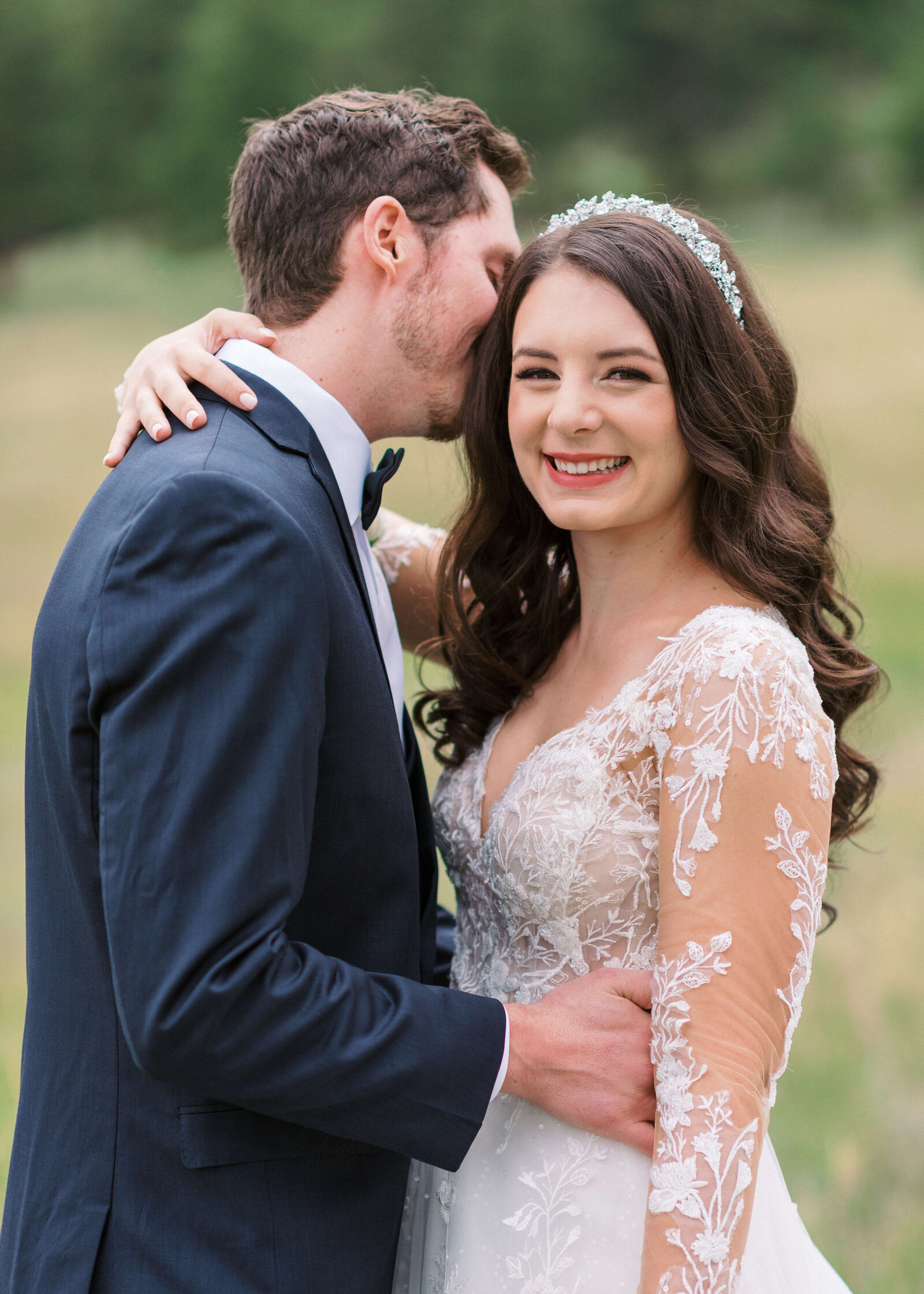 Virginia wedding photographer takes picture of a groom kissing his new bride on the cheek while she smiles at the camera