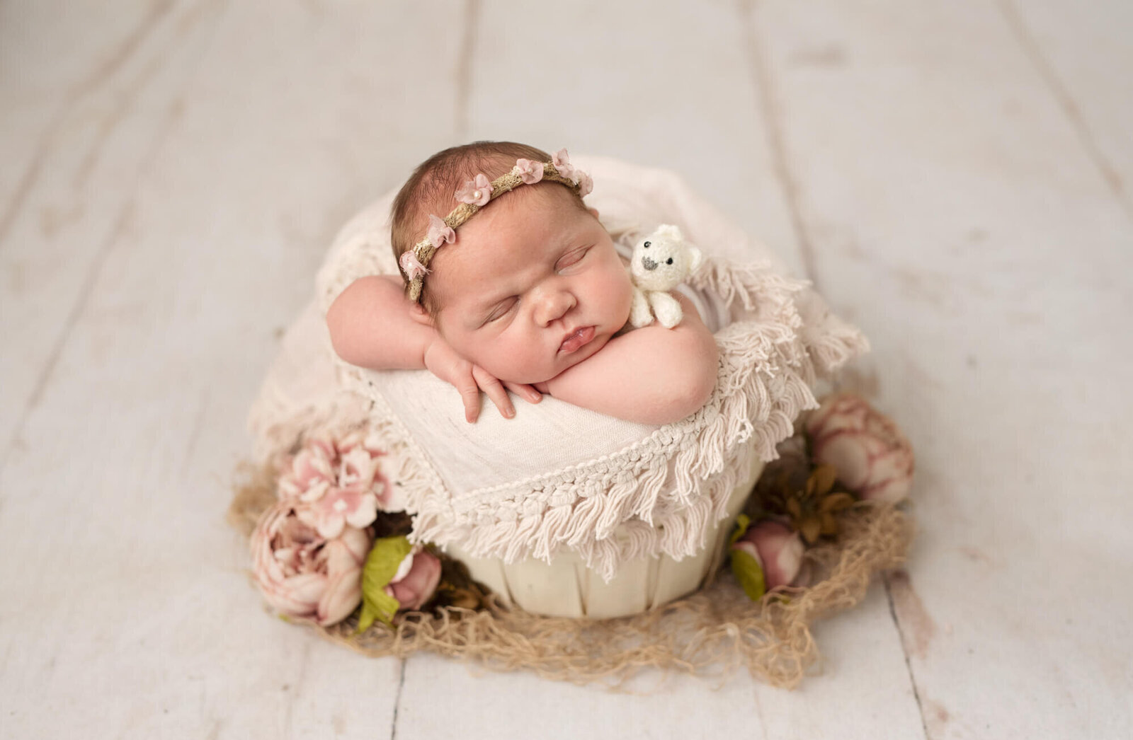 10 day old baby girl in cream bucket with pink layer and flowers