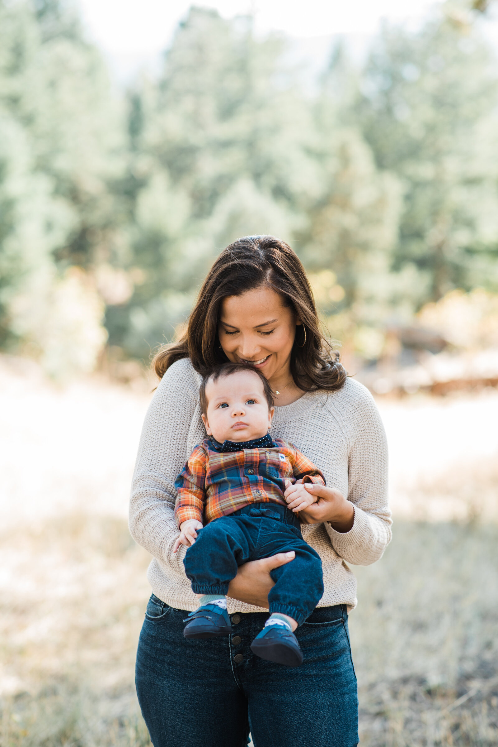 mom and baby smile for denver family photographer while mom holds the baby outward to face the camera