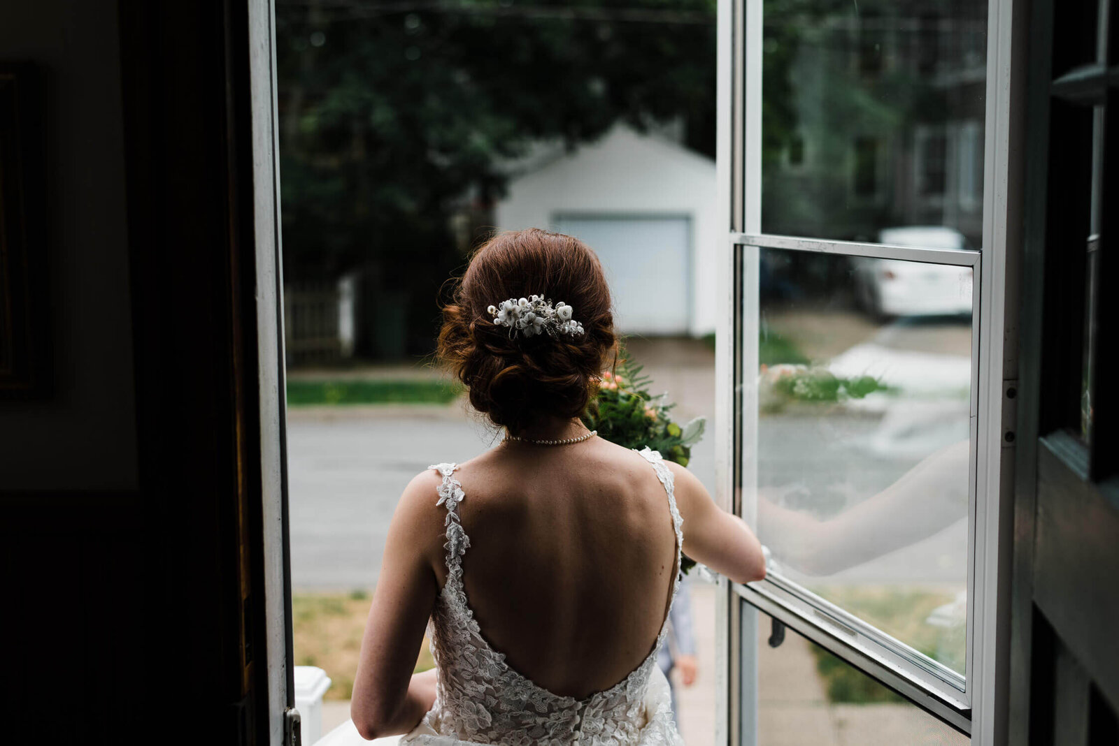 Bride wearing lacy dress, opening front door.