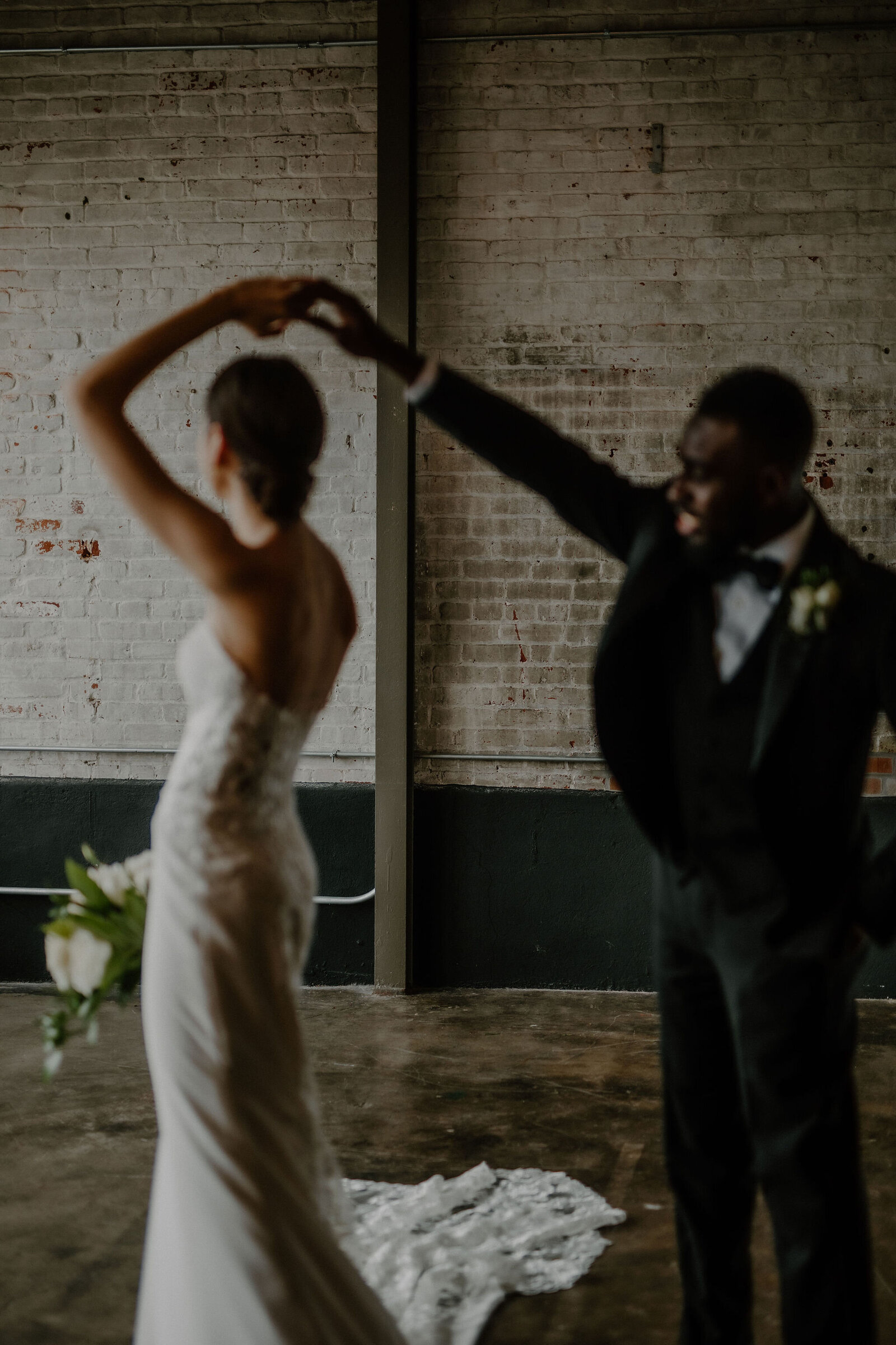 couple dancing twirling in industrial brick space The Bond wedding venue