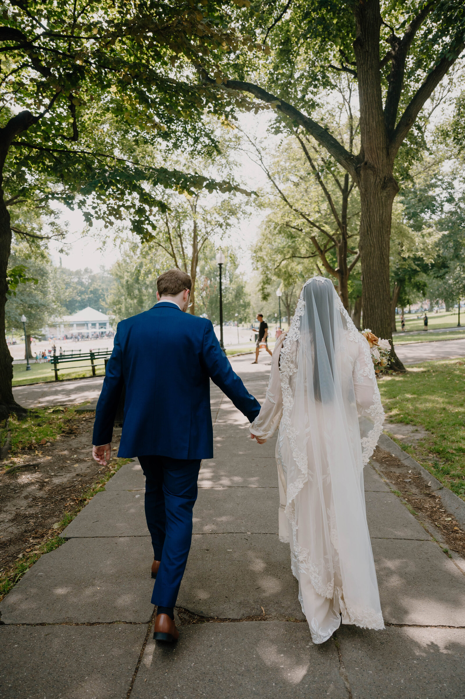 Bride and Groom walking together in Boston Public Garden after their church wedding