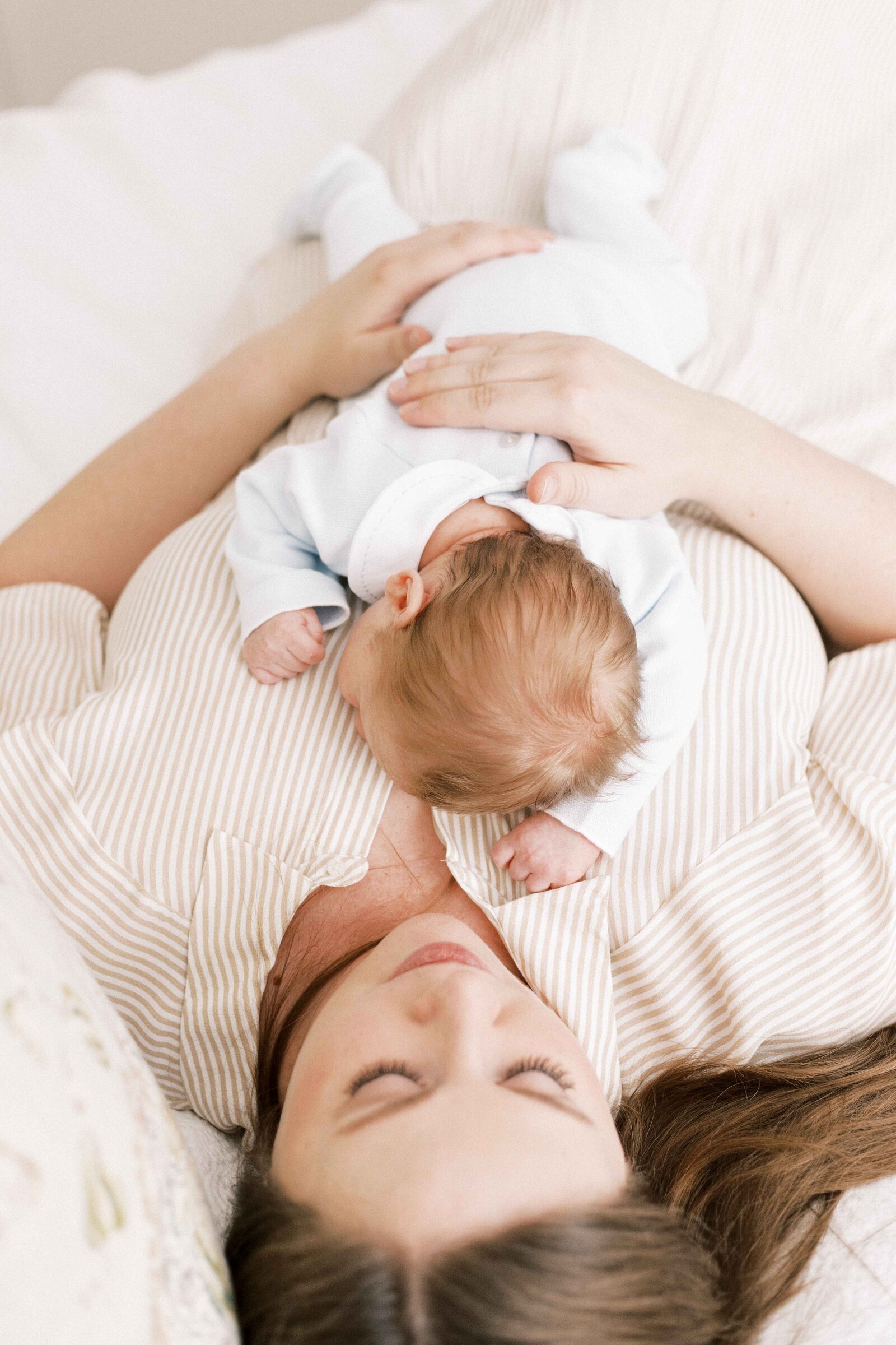 mom laying down with baby inhome during newborn photos in peoria illinois 