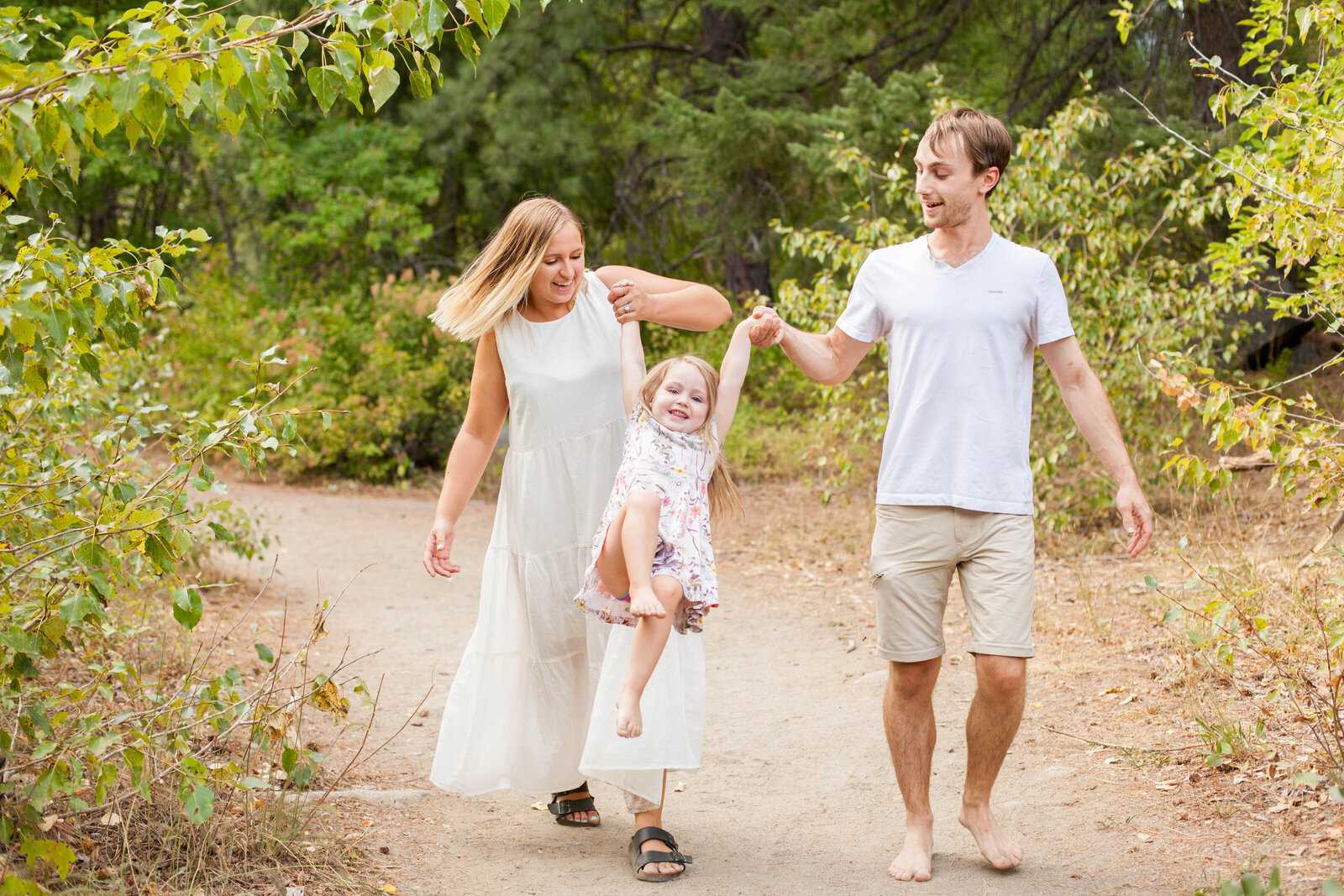 A husband and wife playing with their child on a trail.