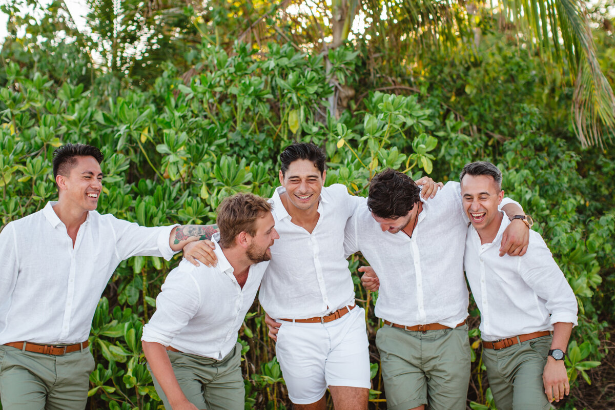 groomsmen laughing and goofing around on beach