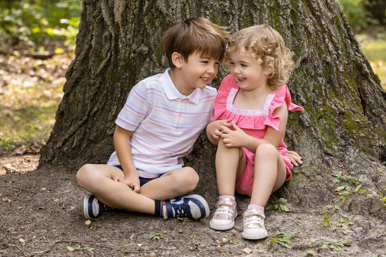 A boy and a girl are sitting next to each other under a tree