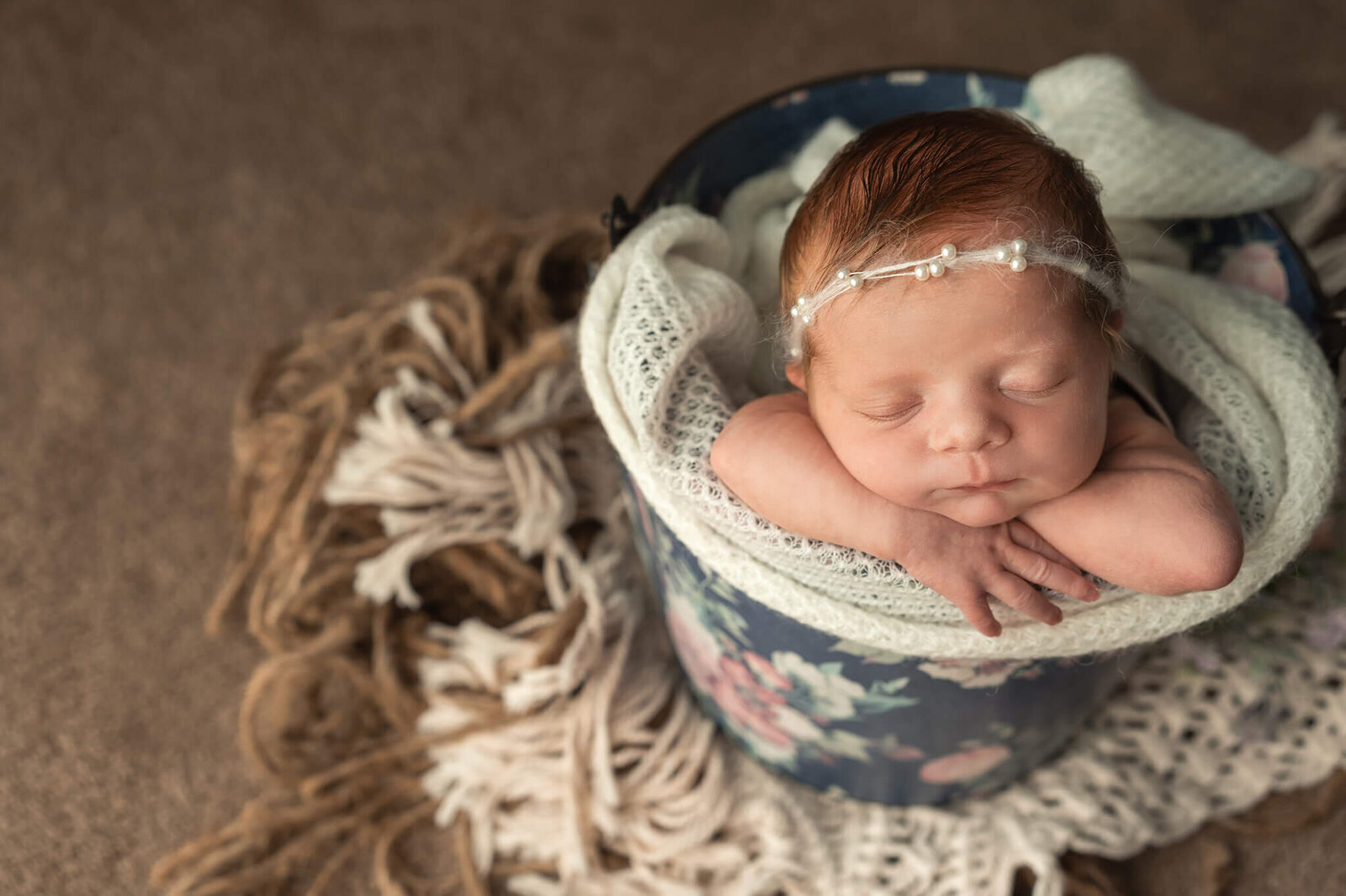 Baby sleeps peacefully in bucket during newborn session