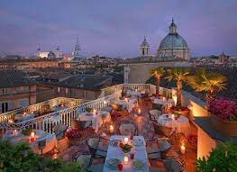 Tables dotting Mater Terrae lounge at Bio Hotel Raphael Relais + Chateaux hotel in Rome at sunset. 