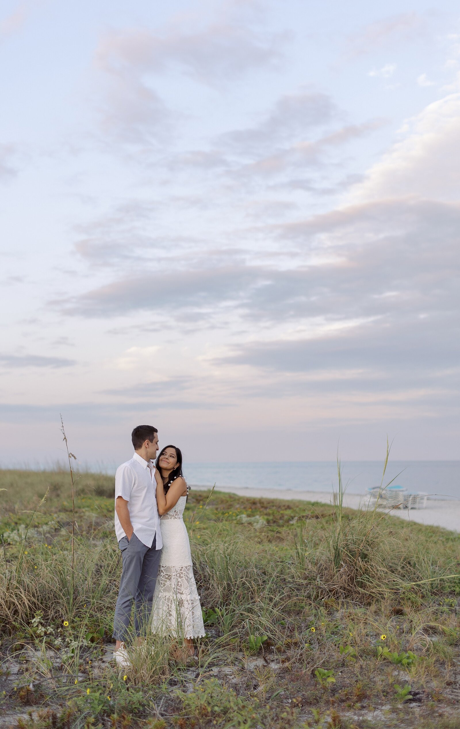 Couple embrace in dunes at sunset in Miami.