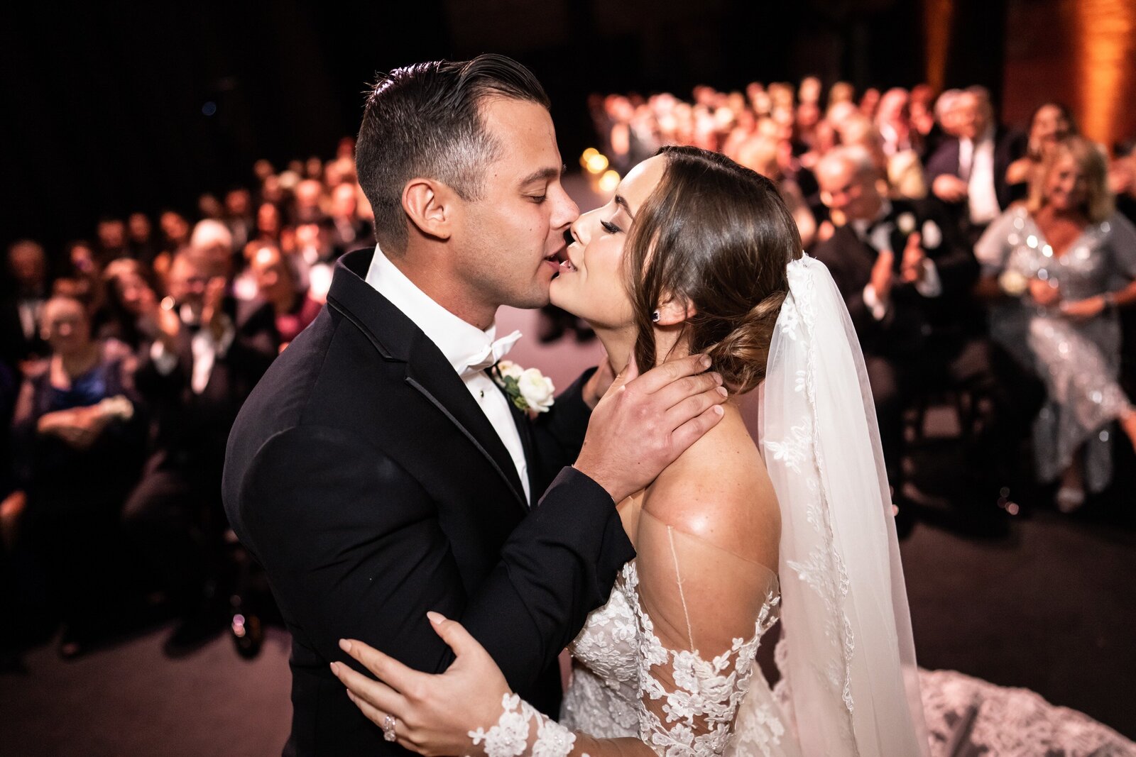 Bride and groom kiss at Civic Theatre wedding ceremony with guests in background