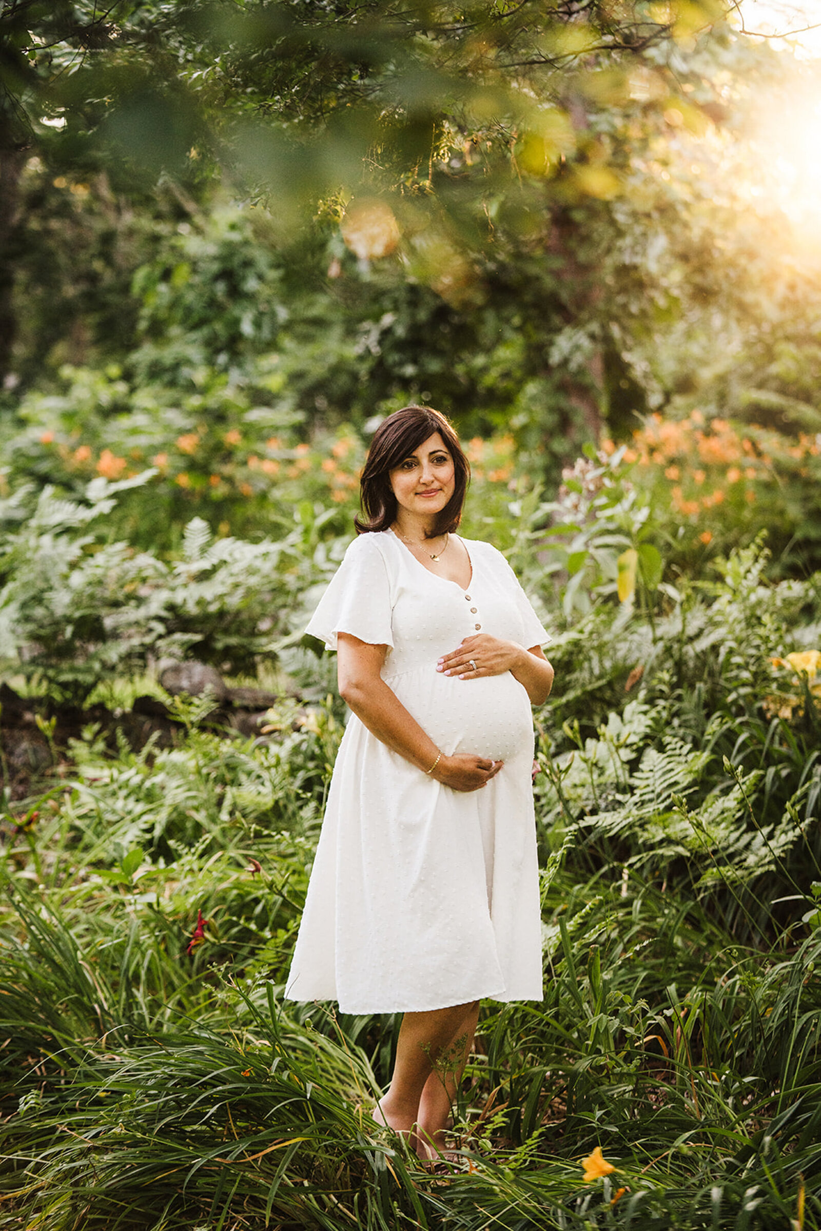 pregnant woman in white stands in forest