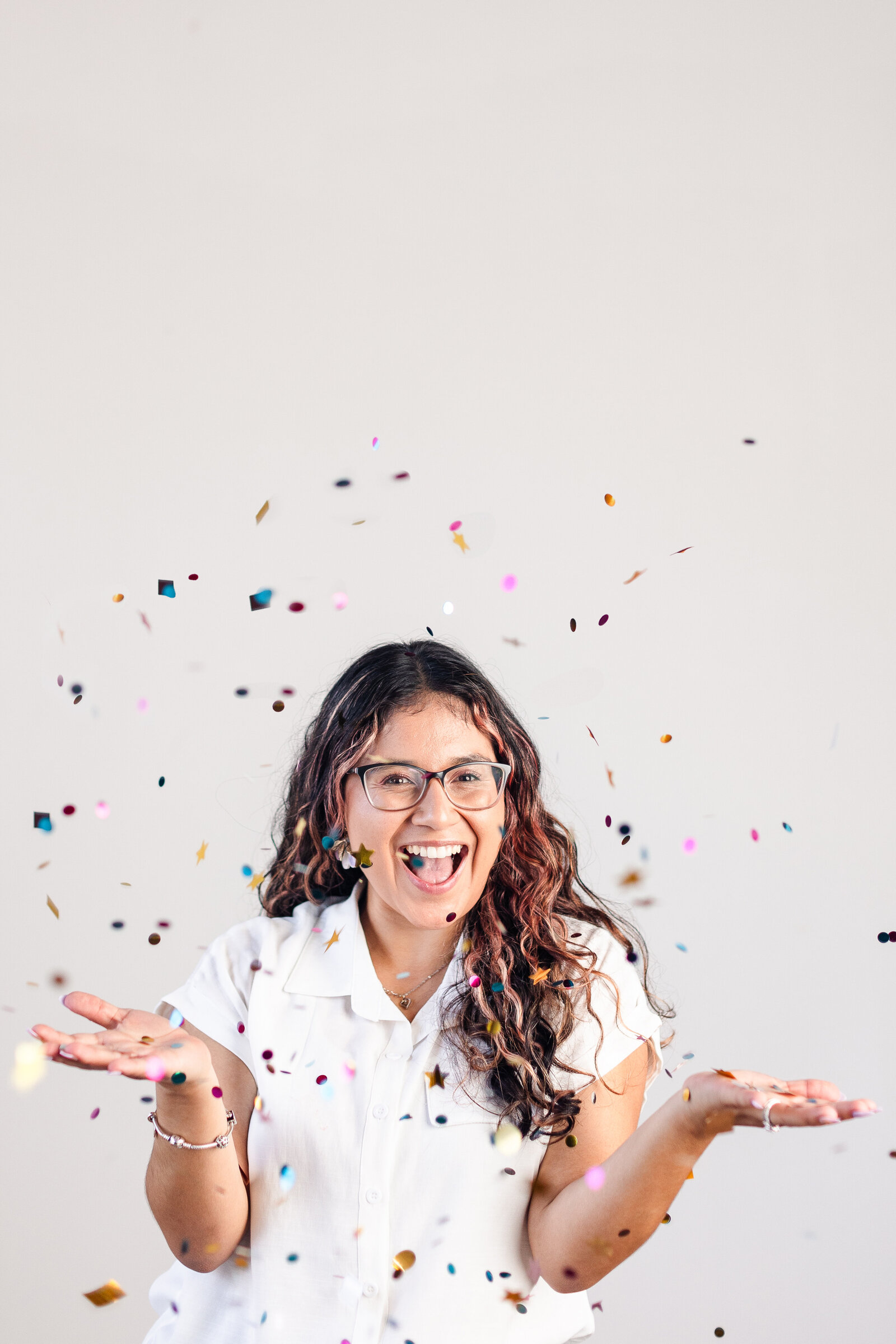 a woman smiles and throws confetti in the air