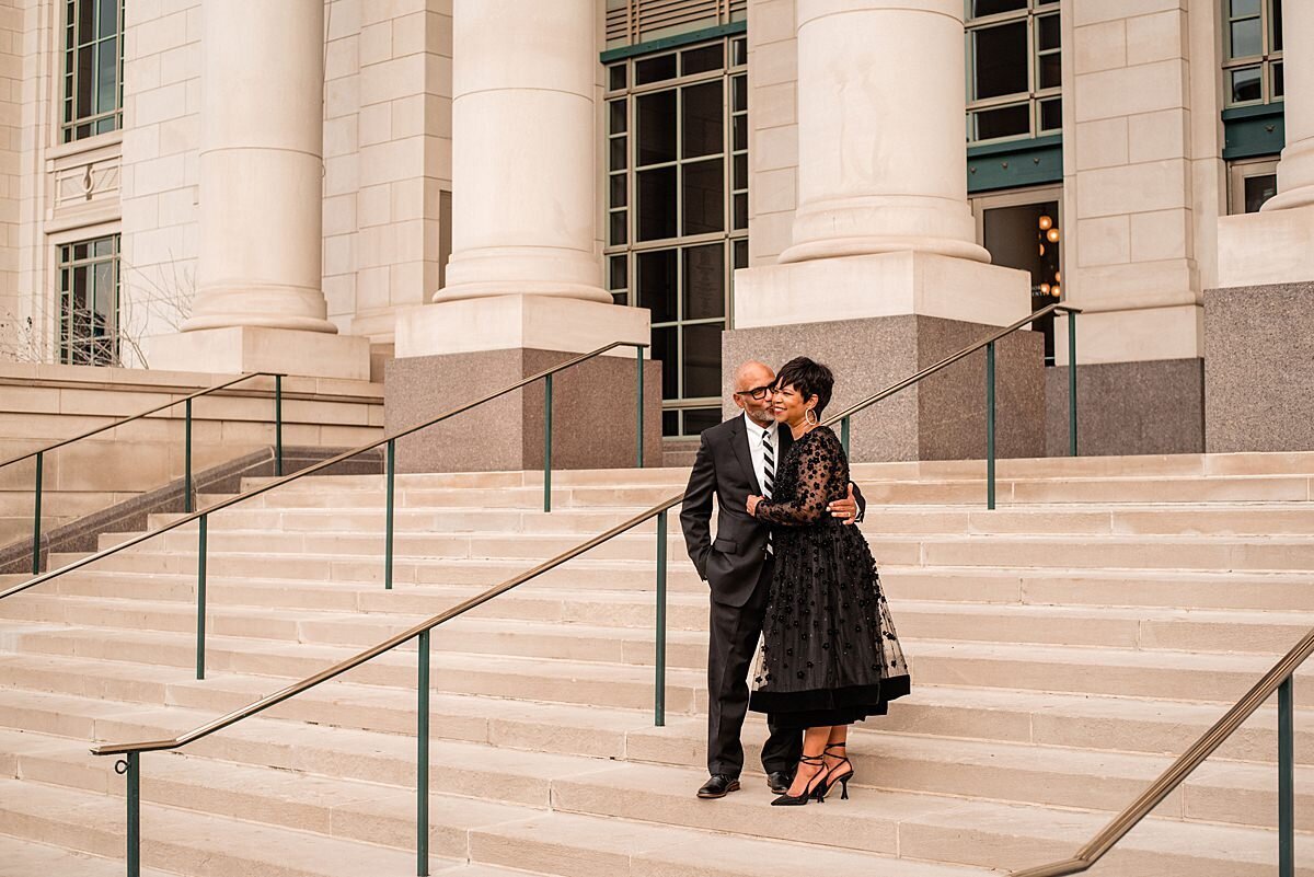 Married couple standing on the steps outside of the symphony center for anniversary photos, they are dressed in formalwear