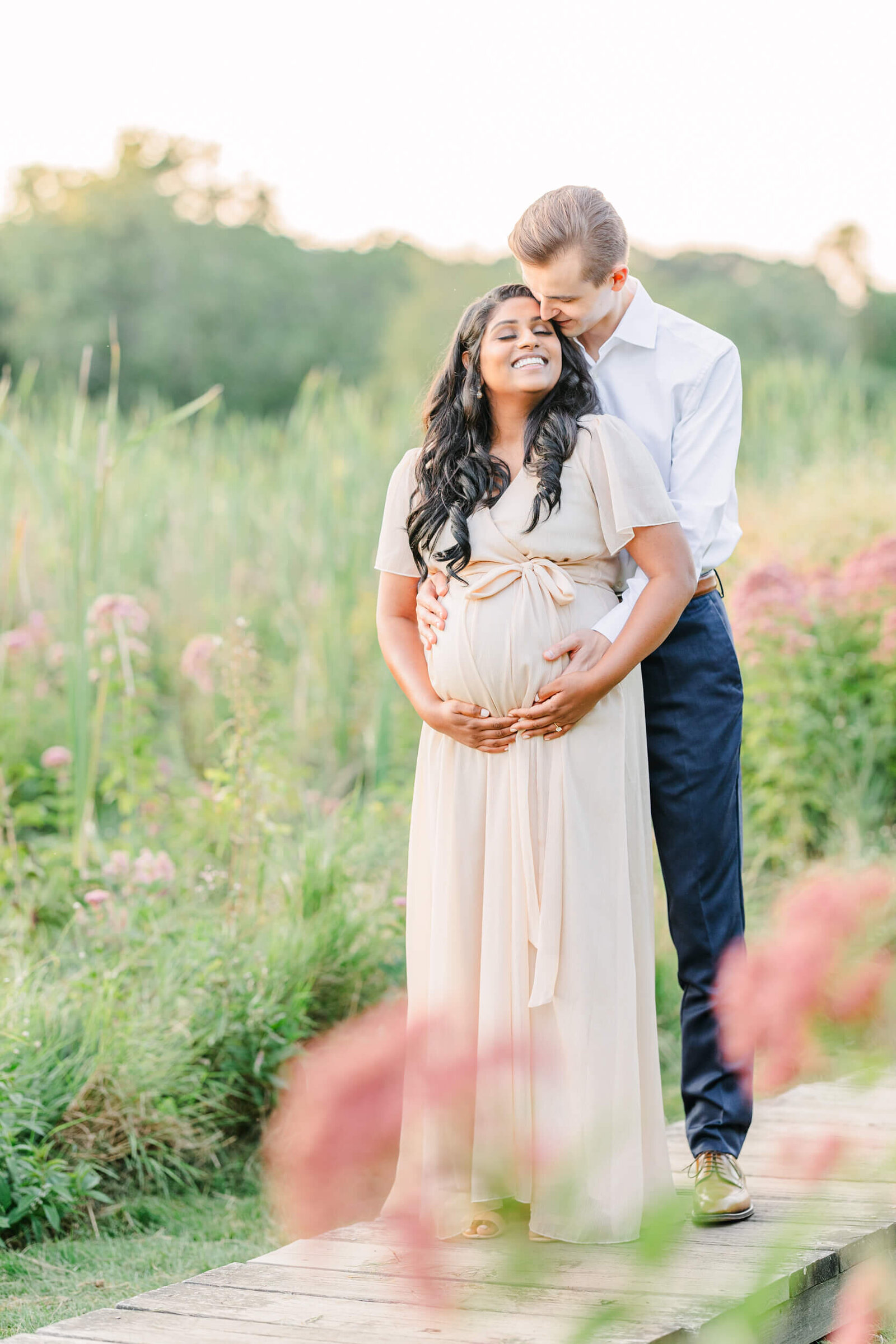 Pregnant woman and her husband cradle her baby bump during a session with a Boston Maternity Photographer