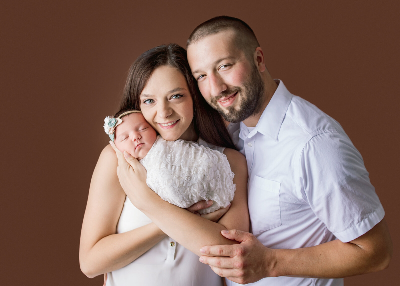mom and dad hugging while mom holds newborn during newborn photoshoot with Nashville, TN  newborn photographer