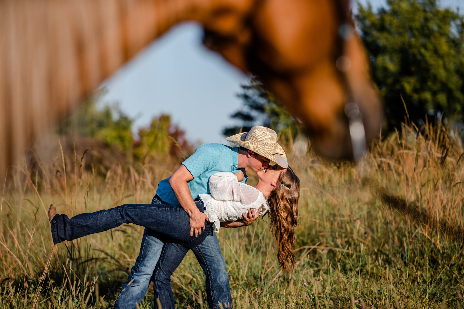 Cowboy dipping girl with horse in foreground