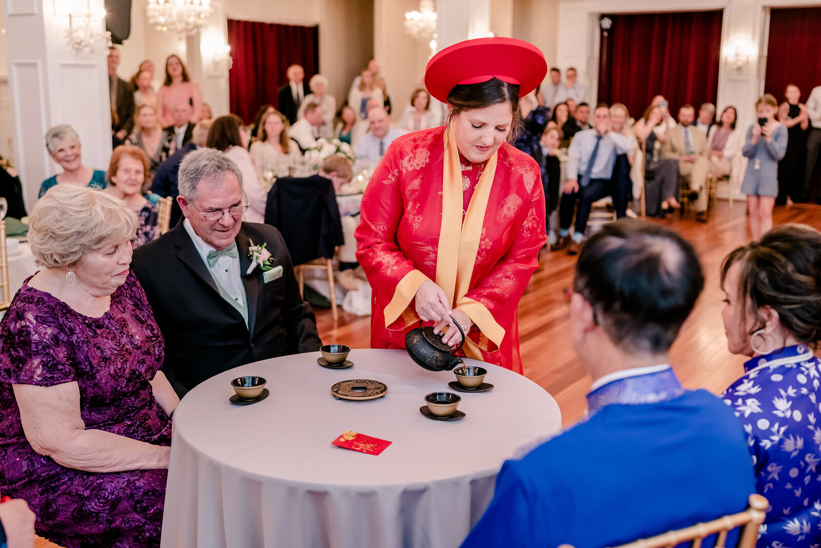 A bride pouring tea during a Vietnamese Tea Ceremony after a wedding at Rose Hill Manor in Loudoun County