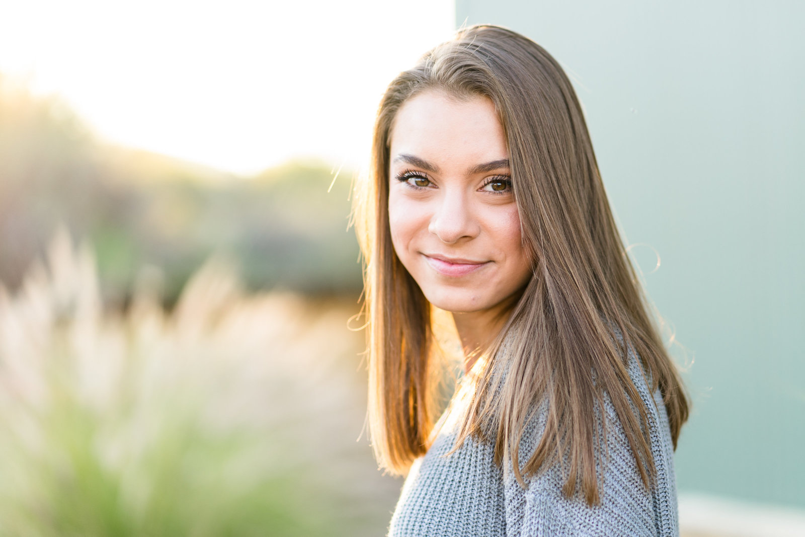 Senior girl smiling at camera in front of green wall