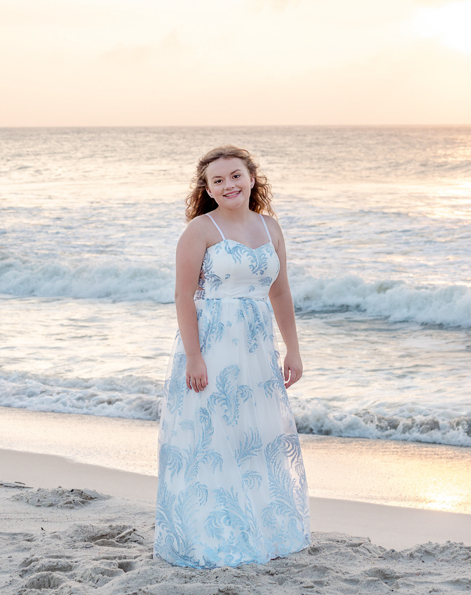  A Wilmington, NC high school senior smiling on the beach with the ocean and dune grass in the background. This vibrant portrait exemplifies casual and natural senior photography, ideal for capturing youthful spirit.