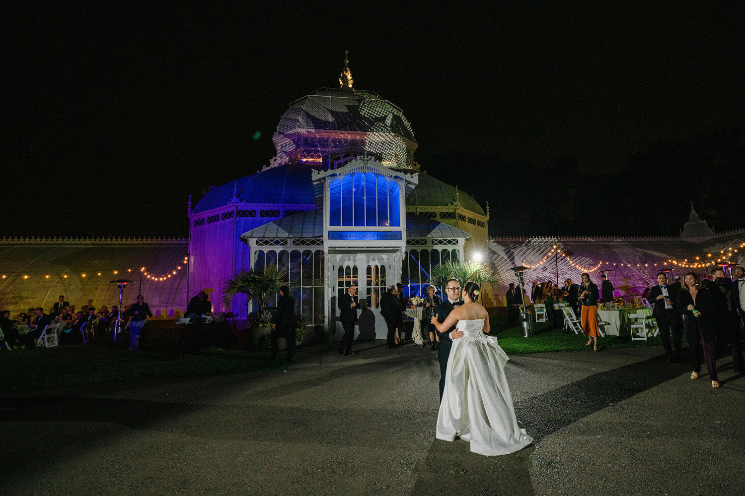 Couple dancing outside glass conservatory at night