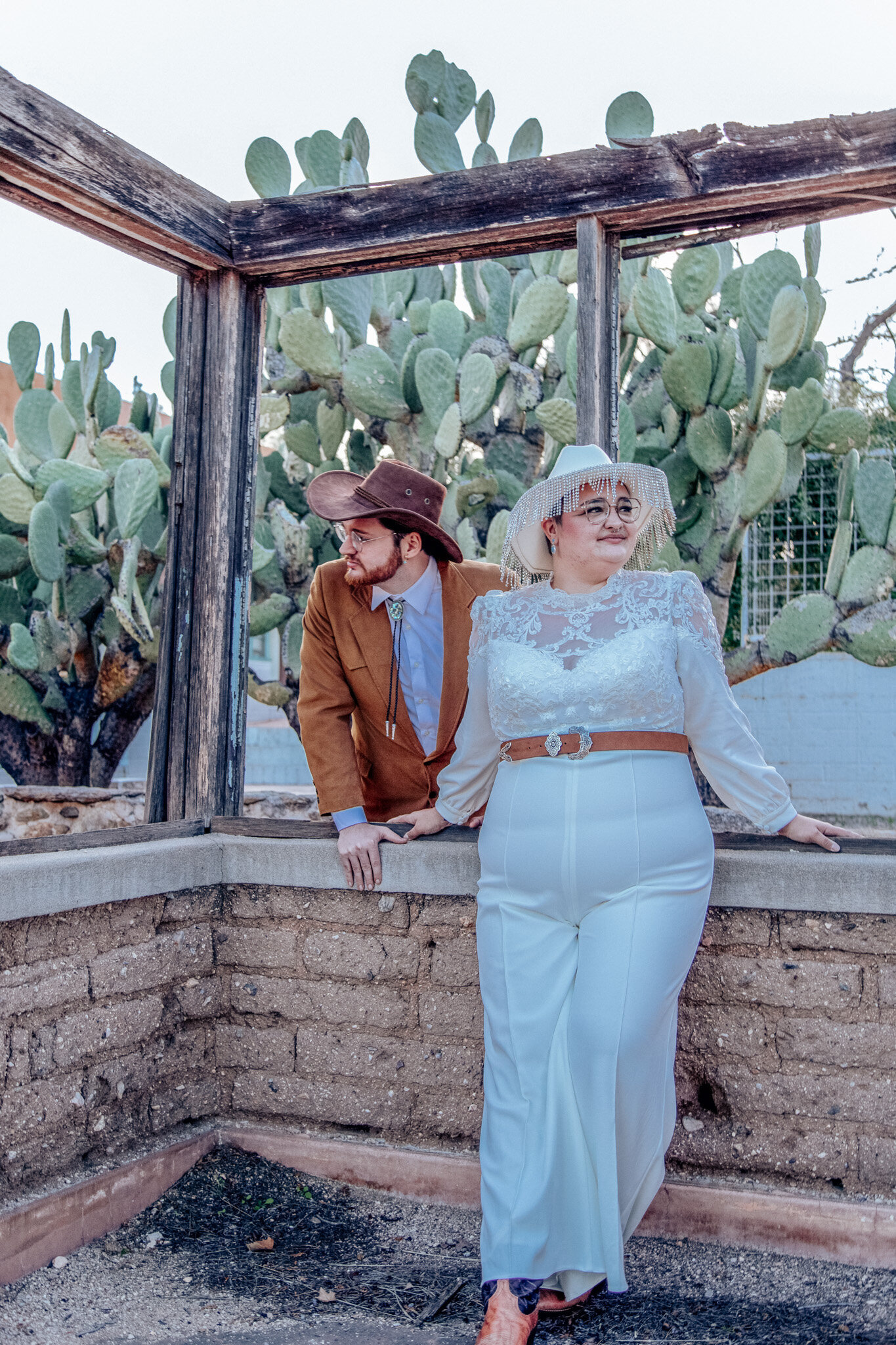 non-binary couple show  western gear in arizona wedding