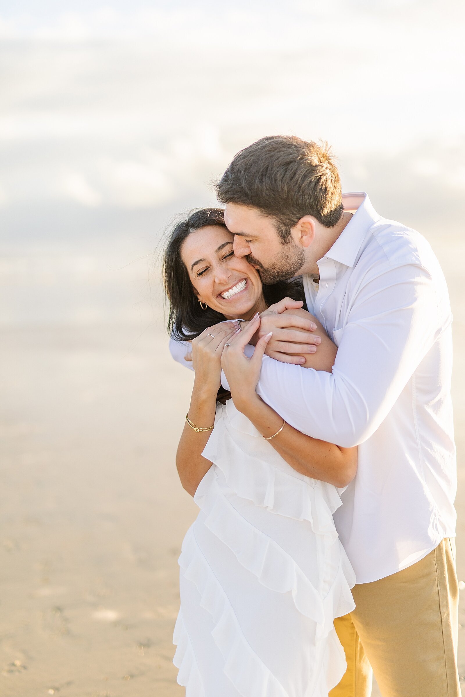 Groom kissing bride on the beach during sunset in Del Mar.