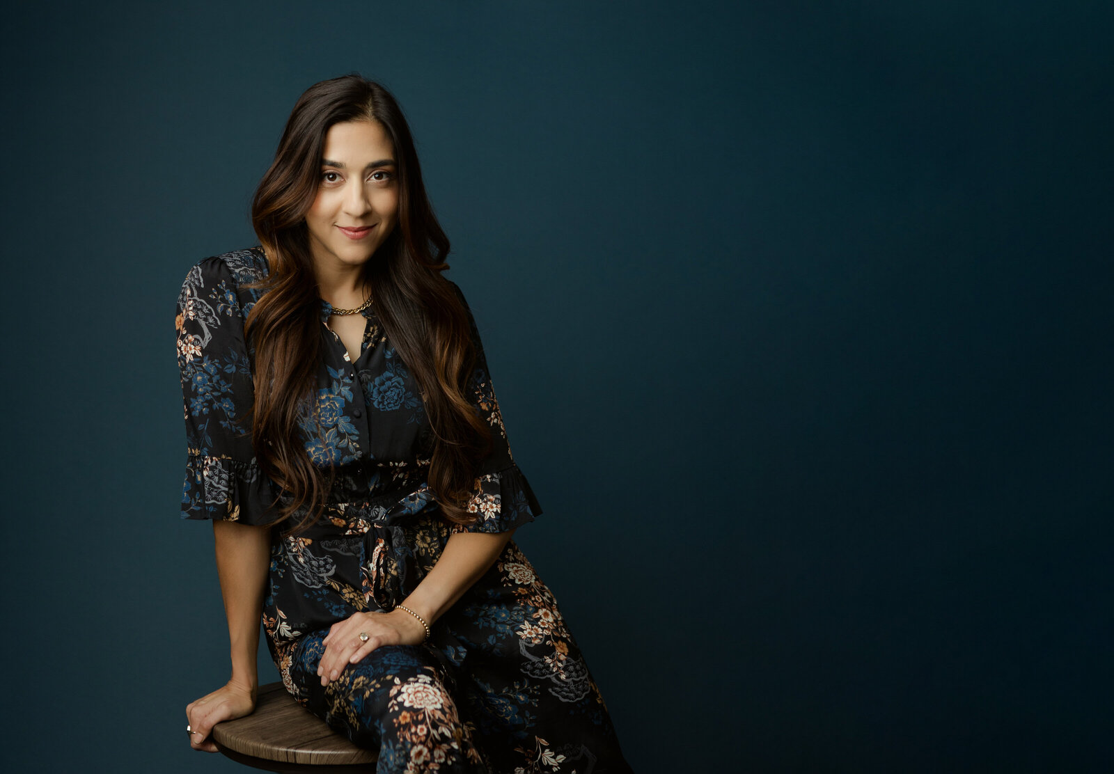 Woman poses for headshot with teal background