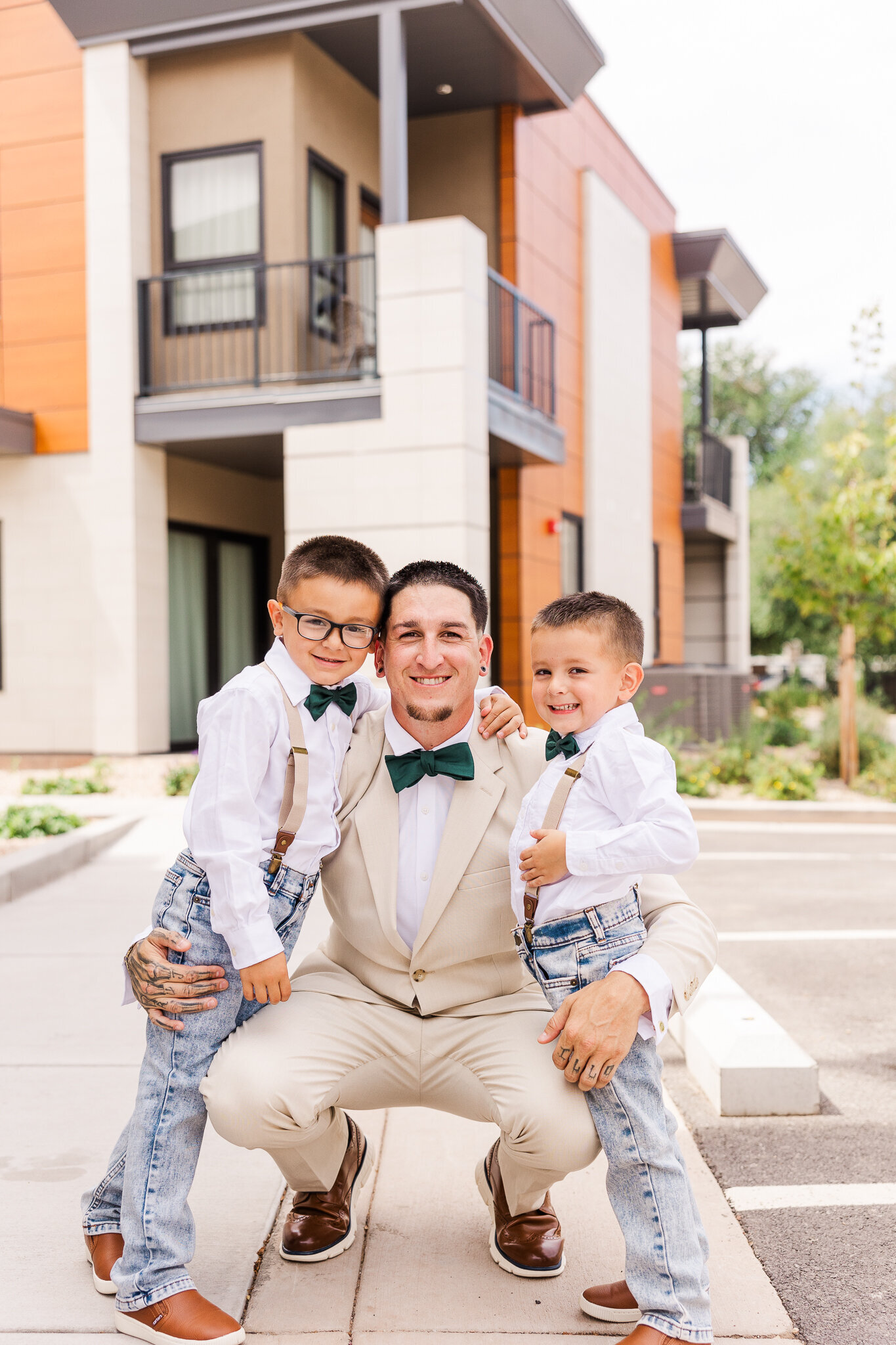 A groom in a white suit hugging his little sons before he walks down the asile for his Moab UT Wedding