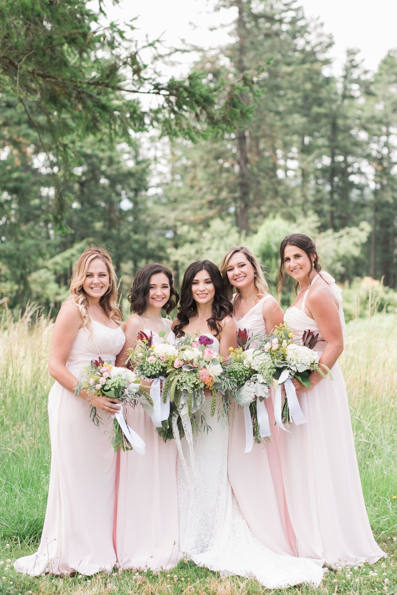 Bridesmaids in blush pink dresses with colorful bouquets at Oregon wedding venue