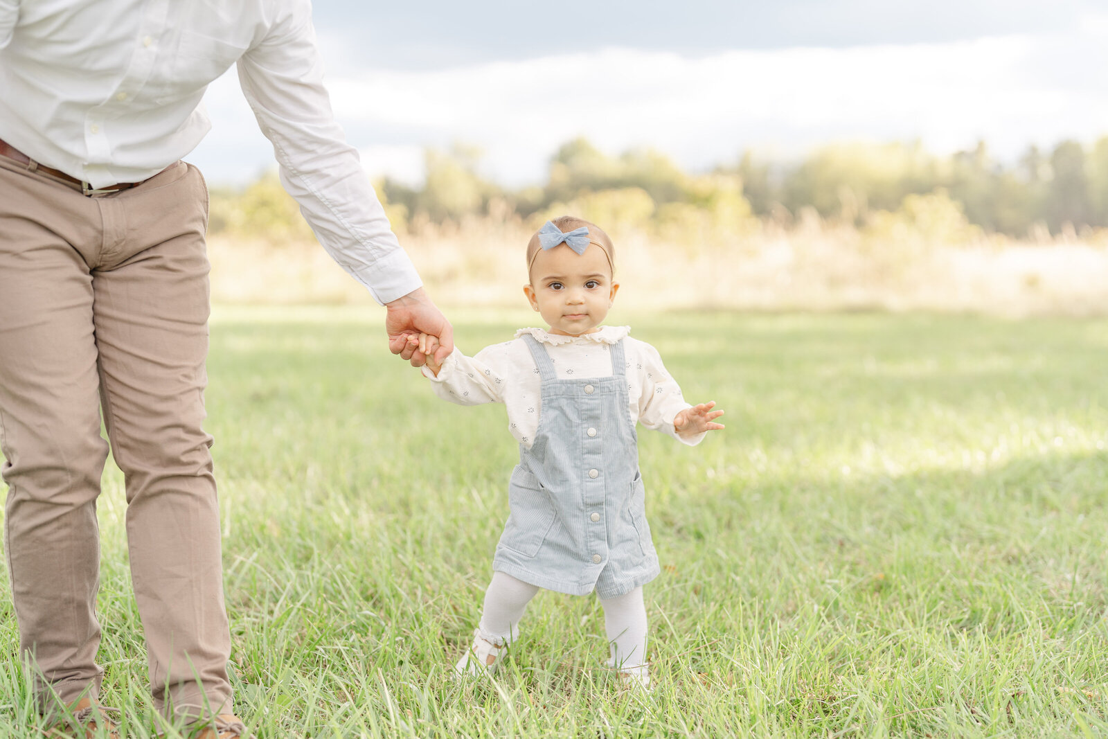 baby holding dad’s hand while walk during family session in Sterling, Virginia