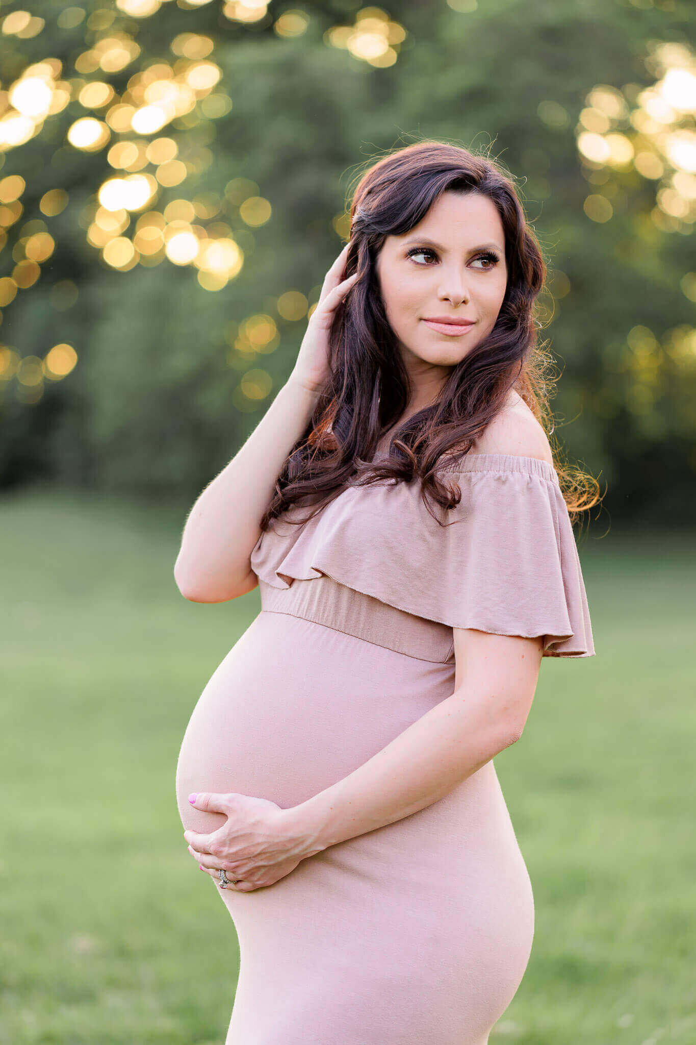 A pregnant woman posing for her maternity photography session at sunset in Burke.