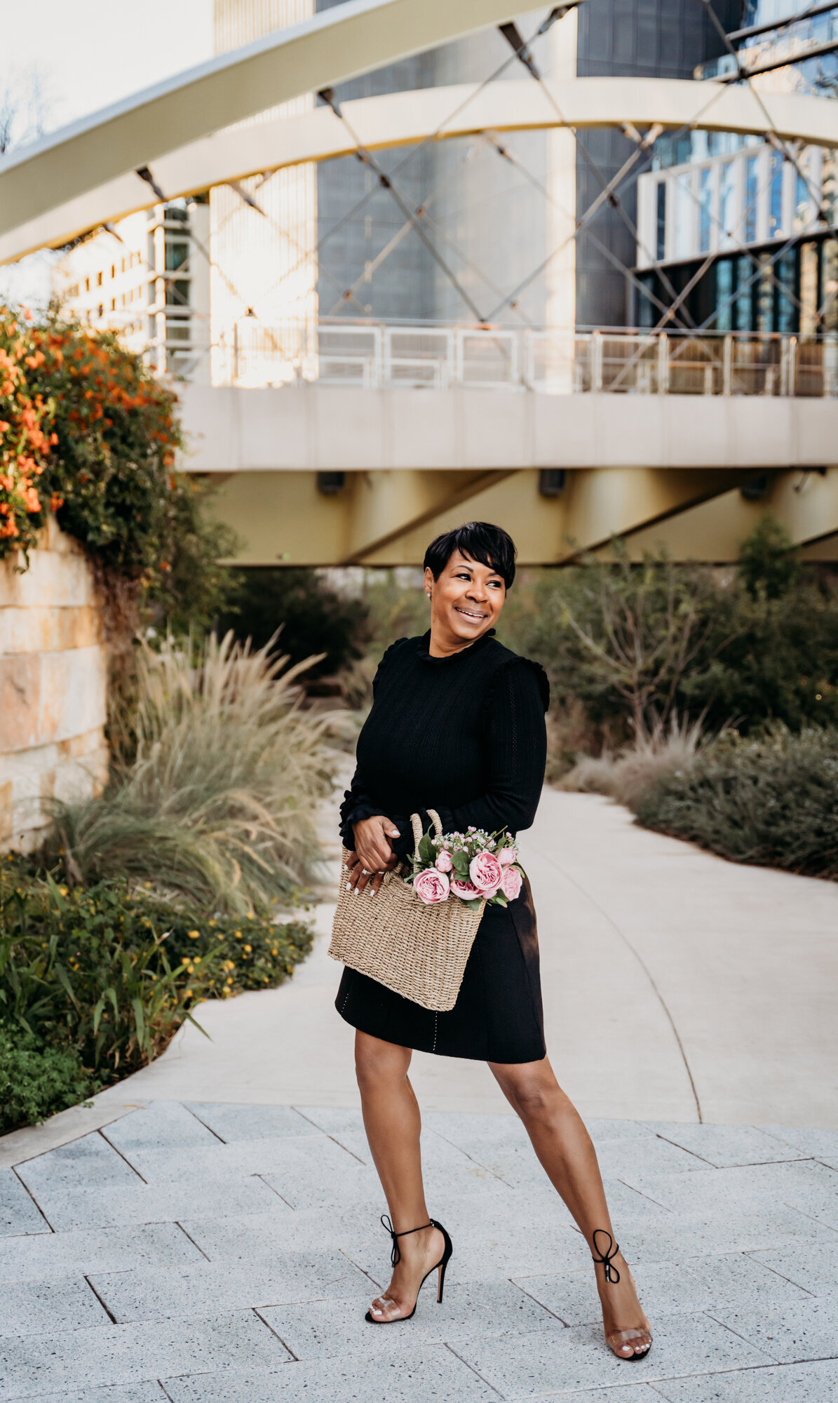 Branding Photographer, a woman dressed up holds a bag with flowers outside