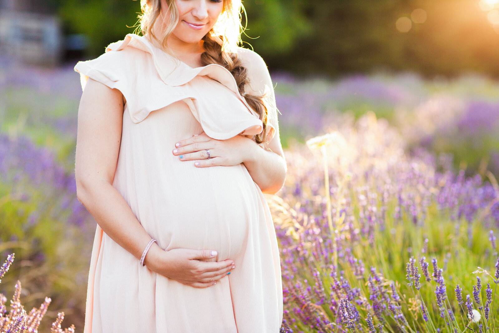 mom to be holding baby bump in lavender field