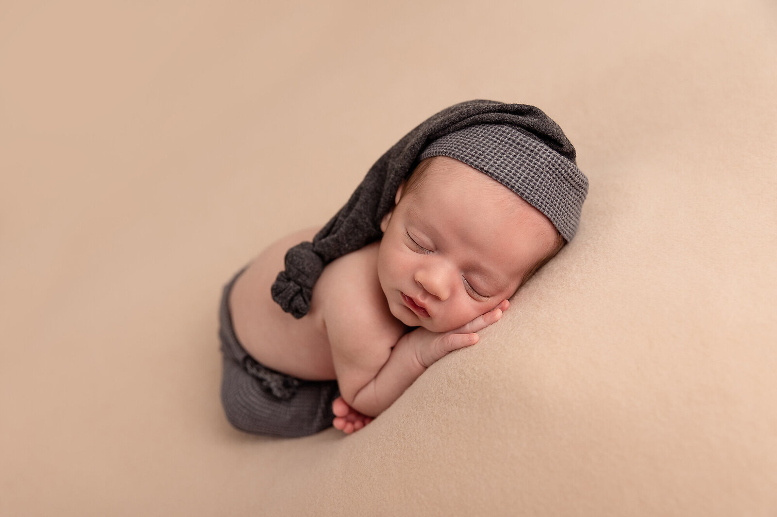 baby sleeping wearing hat and pants by Newborn Photography Bucks County PA