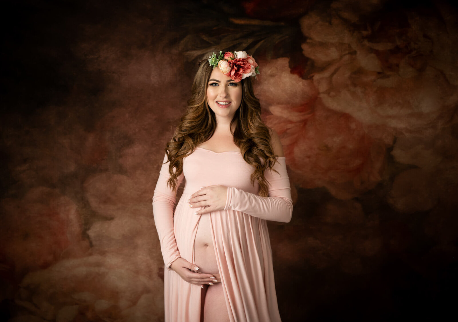 Long haired expectant mother in long pink gown and floral halo