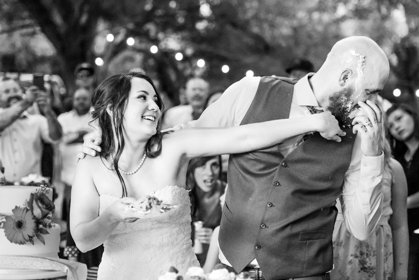 Bride smashing cake into the groom's face with passion.