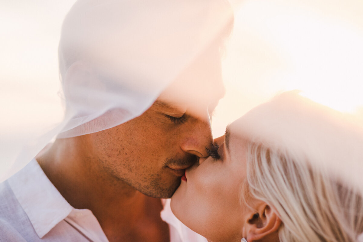 golden hour veil shot of bride and groom kissing