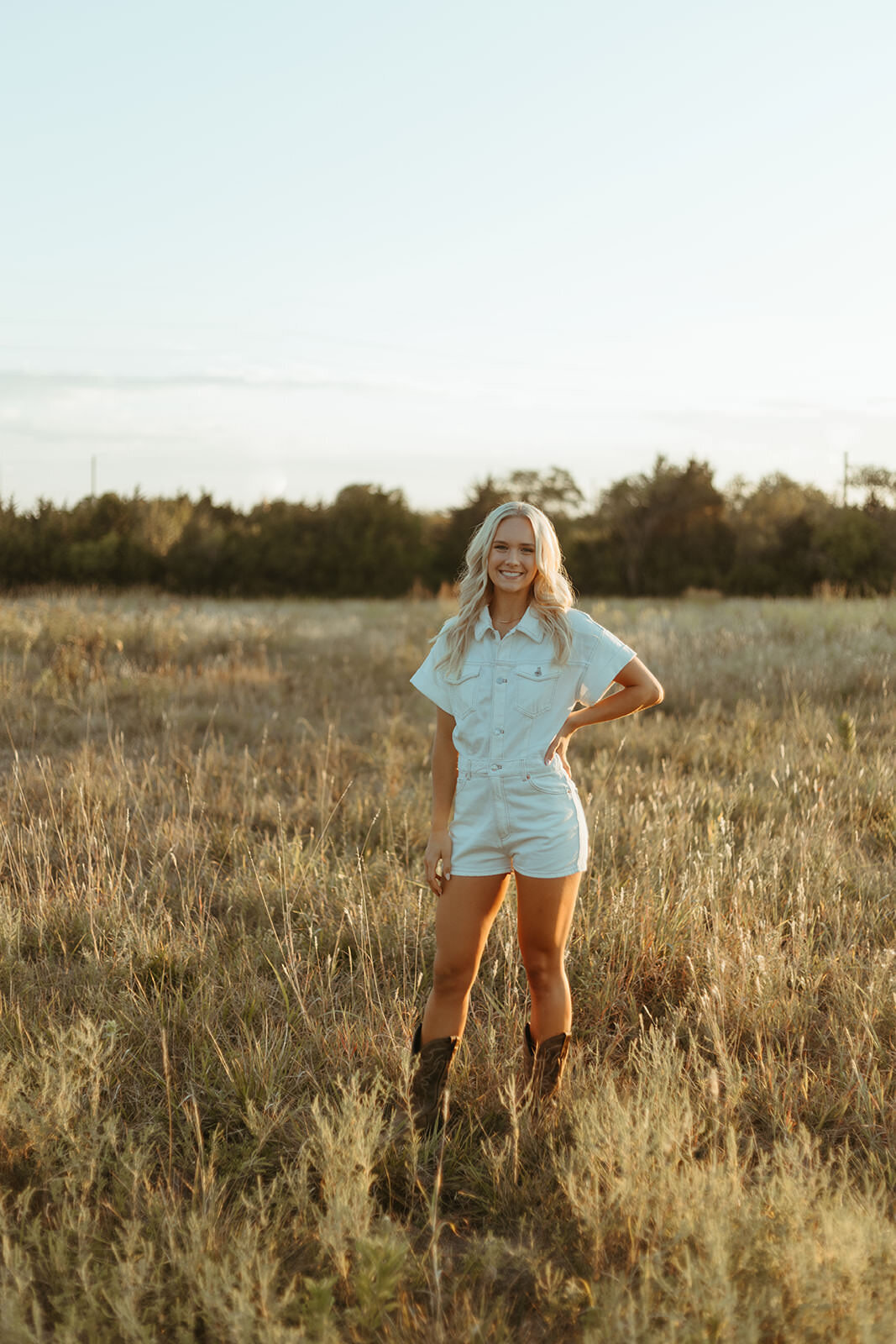 high school senior poses in a field for senior photos with ashley cole photography