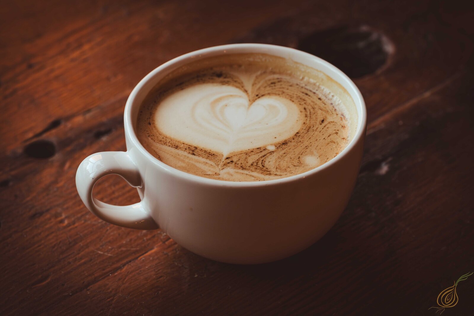 A cup of coffee featuring a heart shape beautifully crafted in the foam on top, set against a neutral background.
