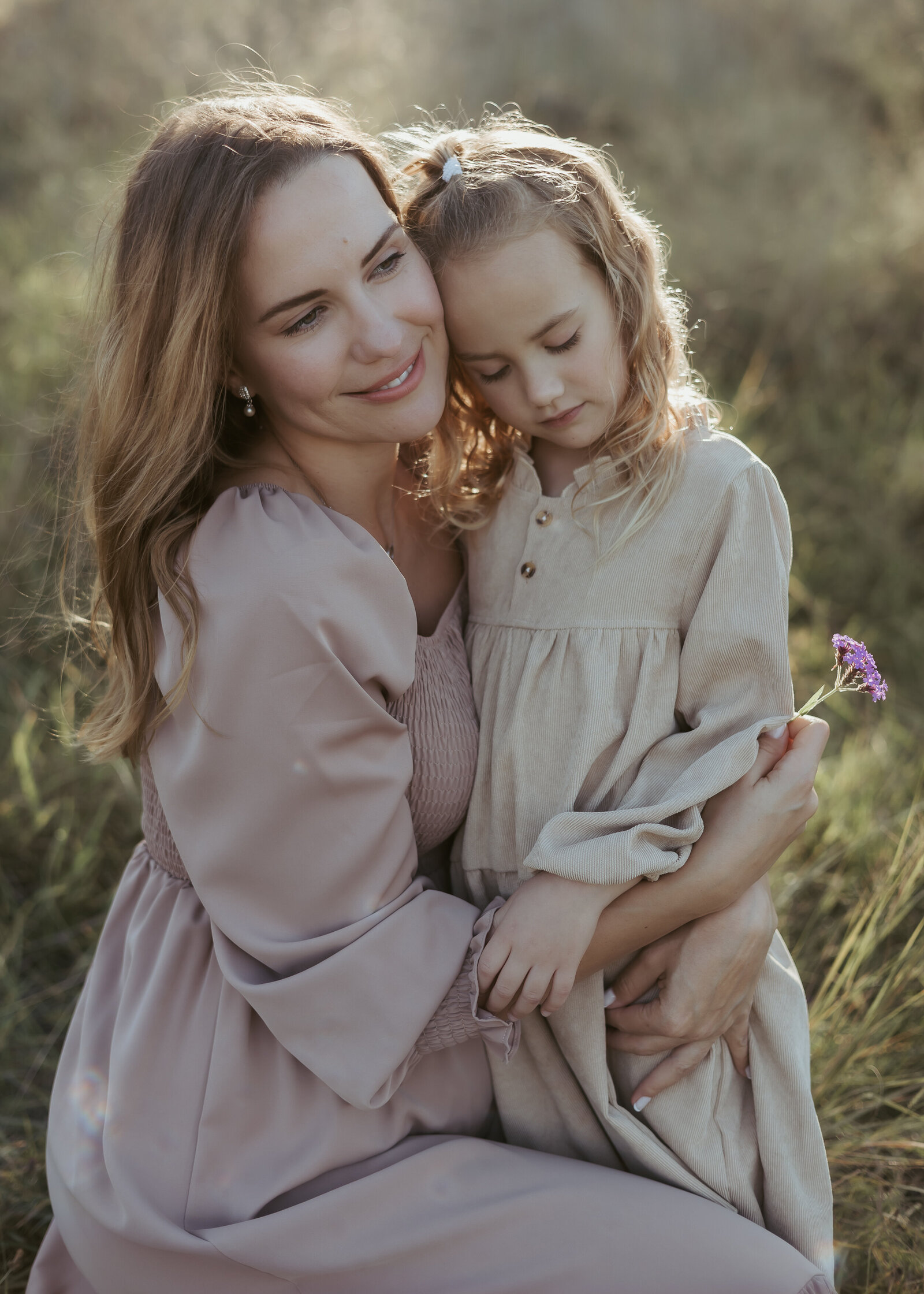 Mother and daughter cuddling close and their heads together for an intimate motherhood family photography experience.