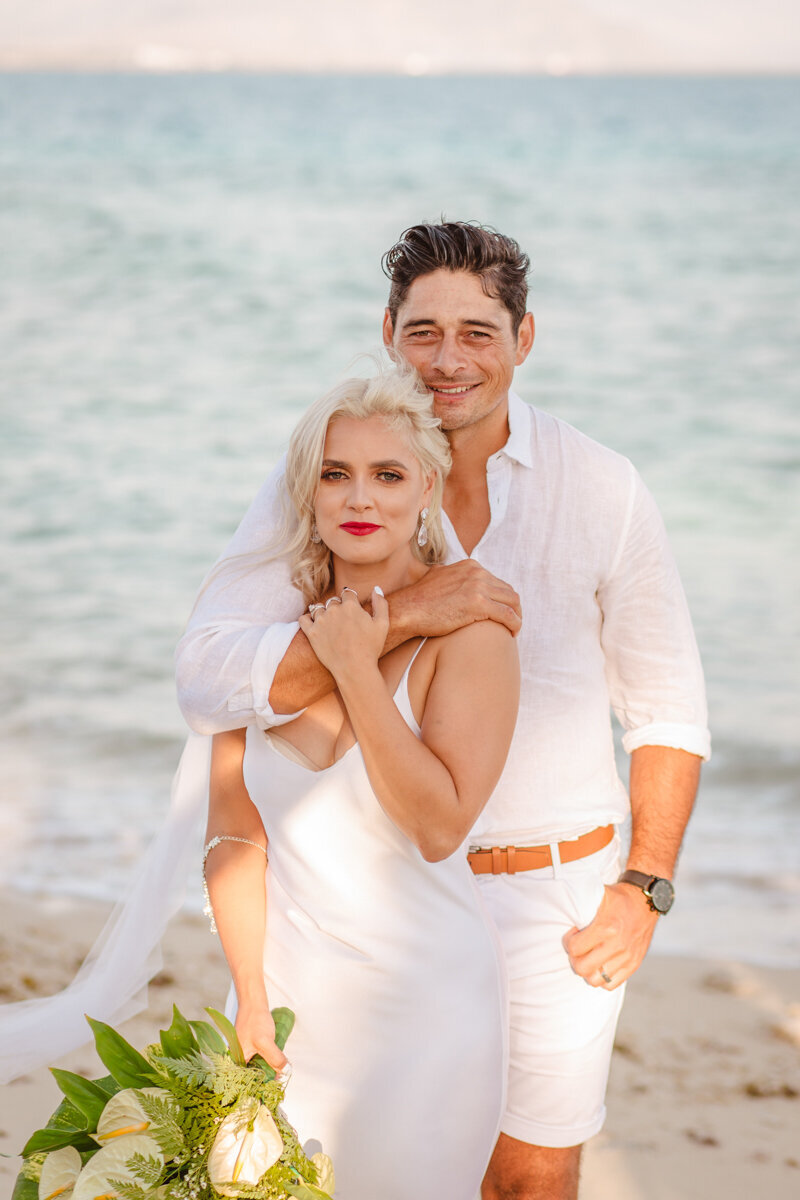 Bride and groom looking at camera on gorgeous beach