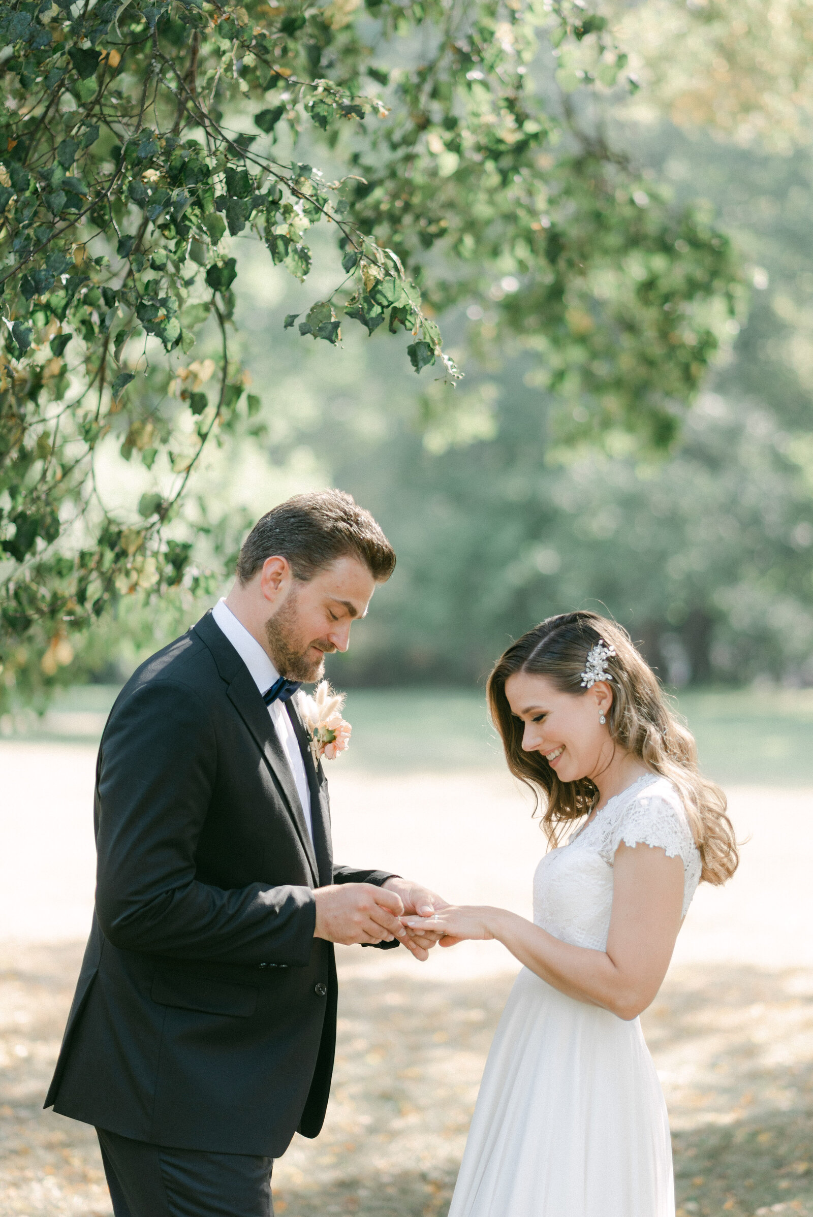 The groom is putting a wedding ring on the bride's finger during their wedding photography with photographer Hannika Gabrielsson.