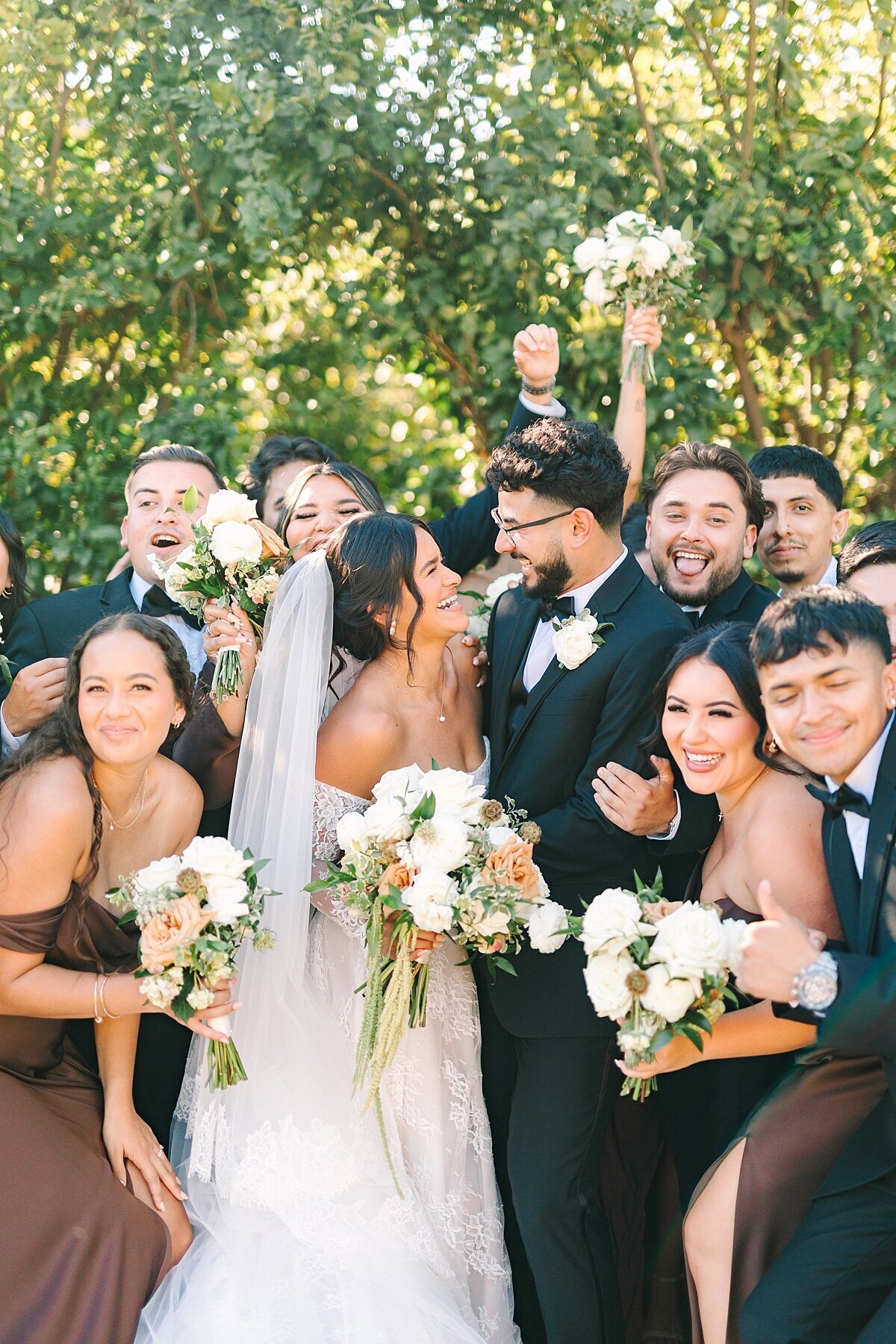 Bridesmaids, groomsmen, bride, and groom laughing and hugging at the Terrace venue at Rancho Guejito Vineyard.