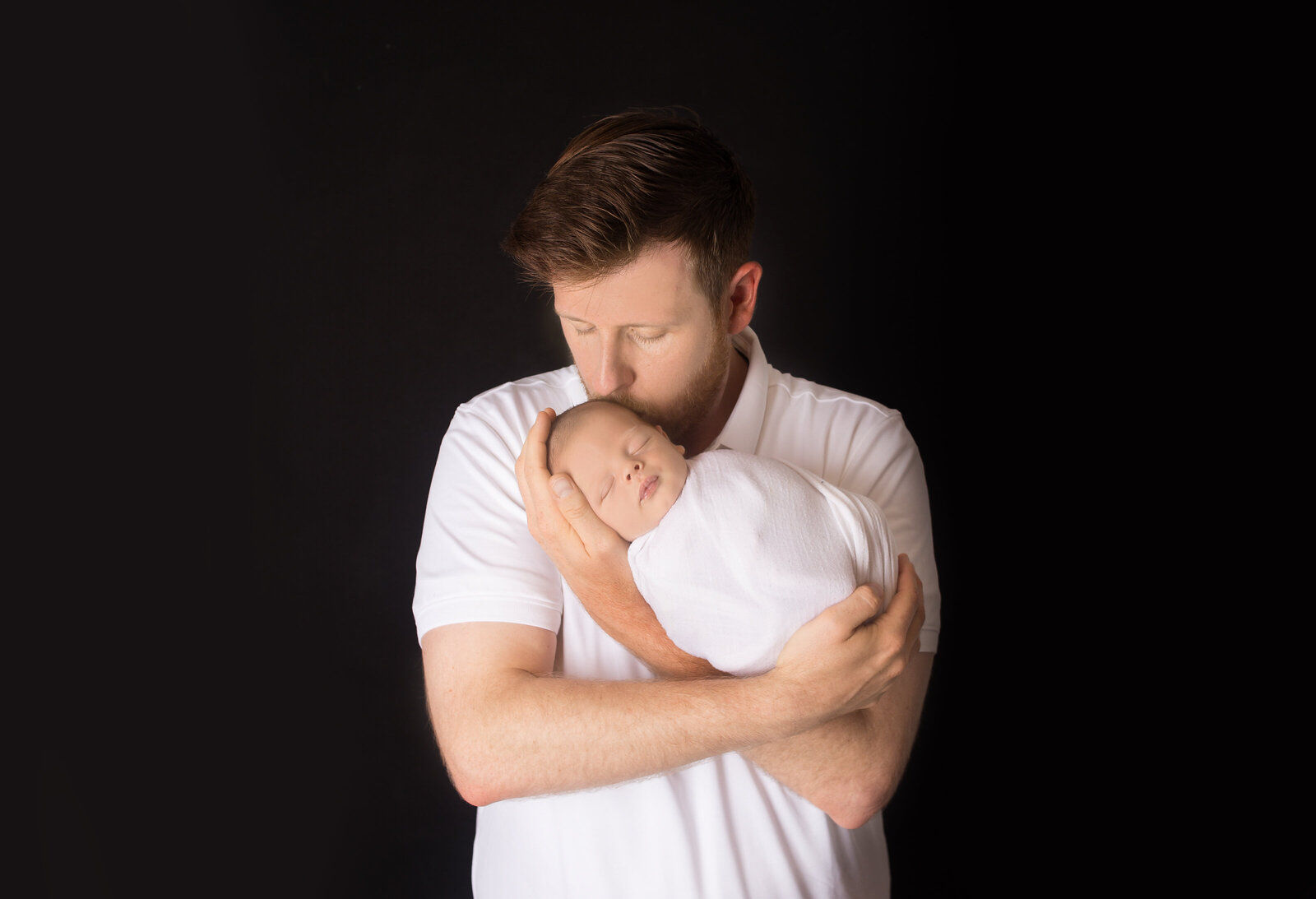 Dad kissing baby boy on head while snuggling him  during newborn photoshoot with Nashville TN photographer