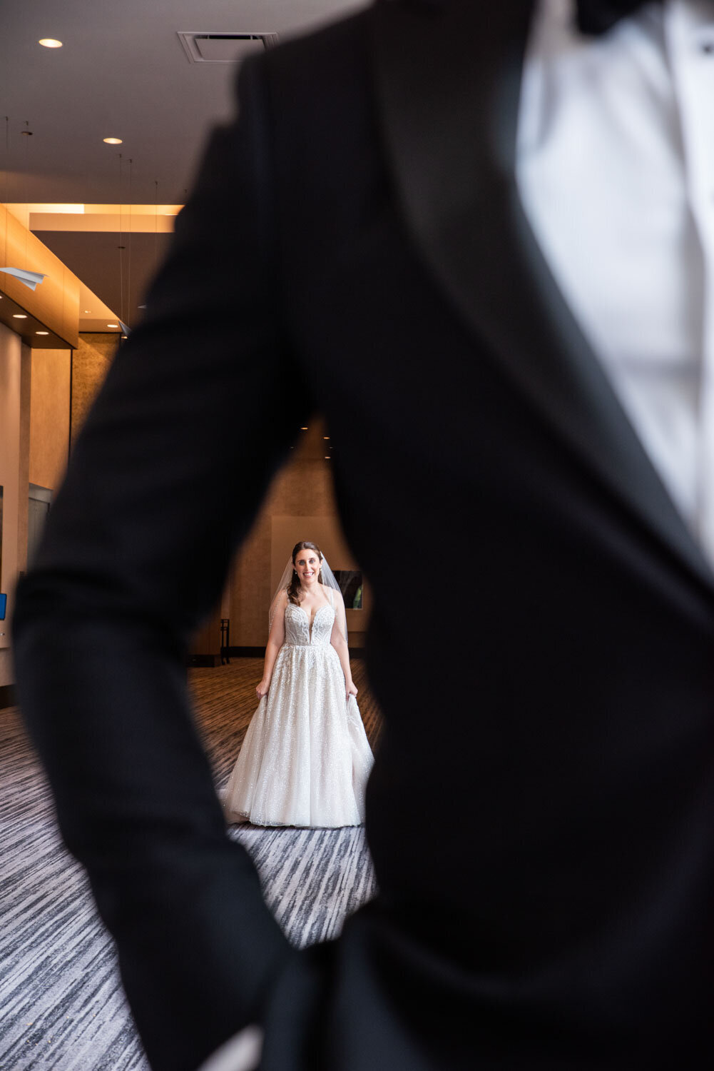 A bride in a wedding dress is standing in front of a man in a tuxedo